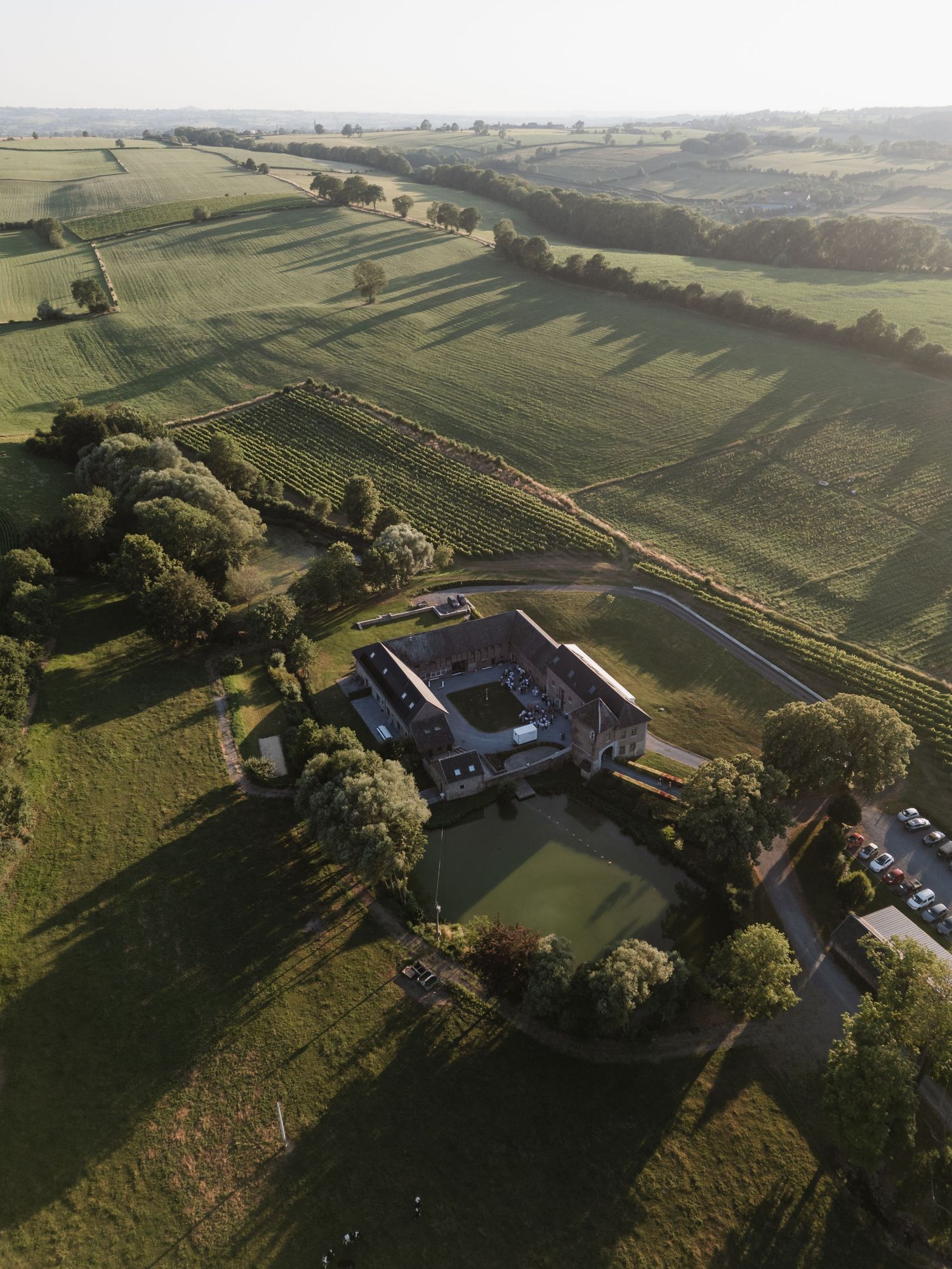 Aerial view of a countryside wedding venue surrounded by rolling green hills at golden hour.