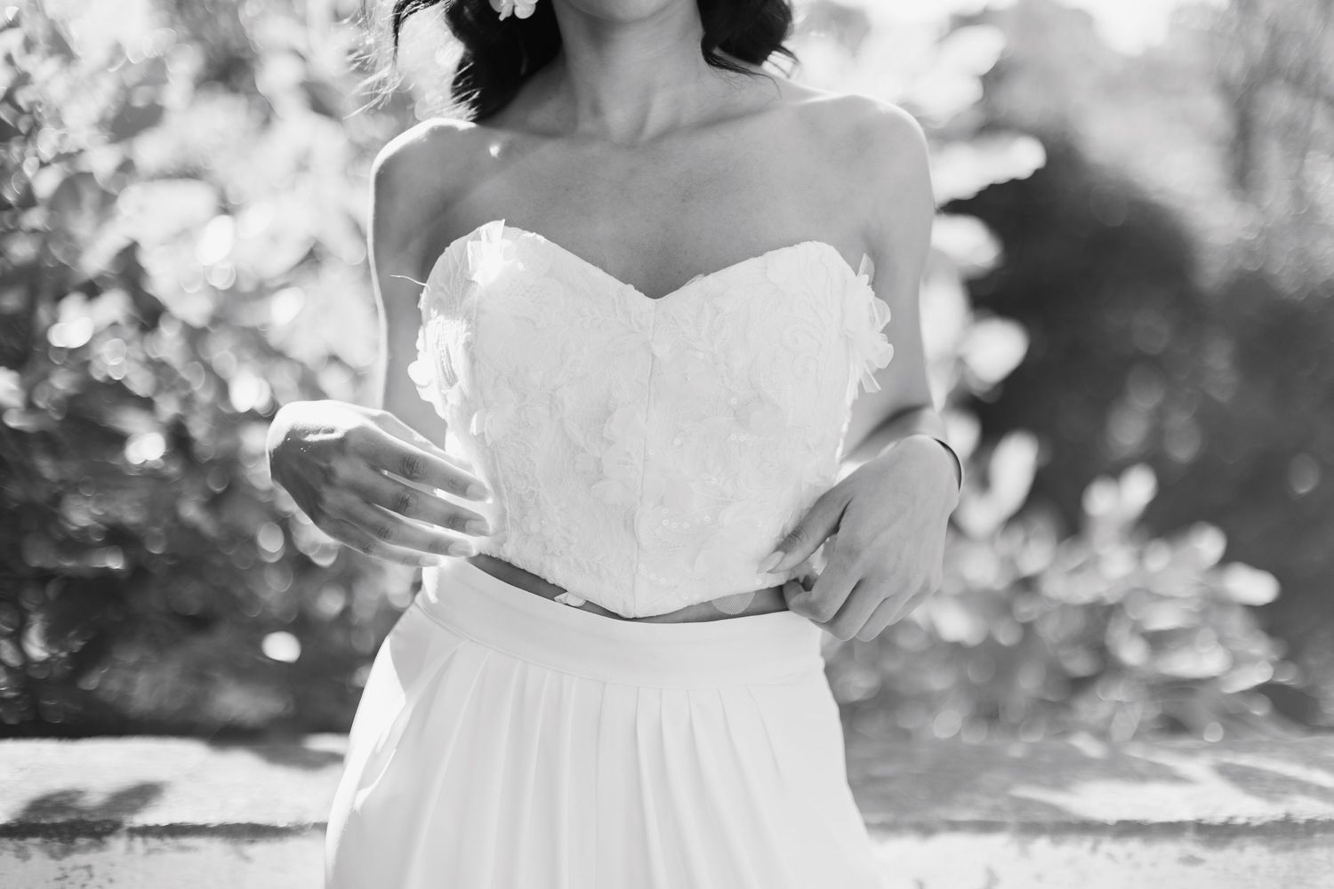 Bride in strapless white floral corset top and flowing skirt outdoors in black and white.