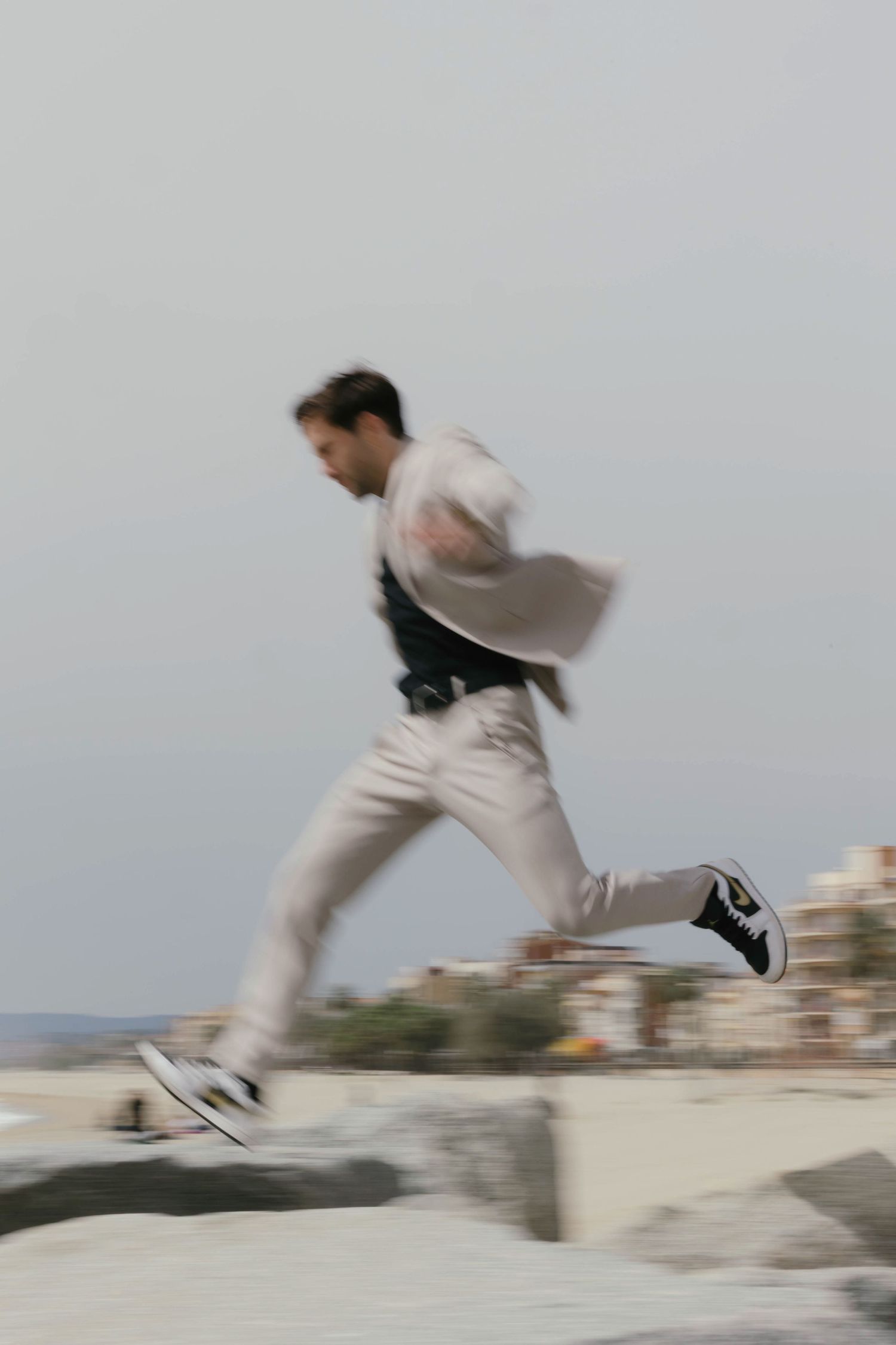 Dynamic blurred motion shot of a man running and jumping over rocks outdoors.
