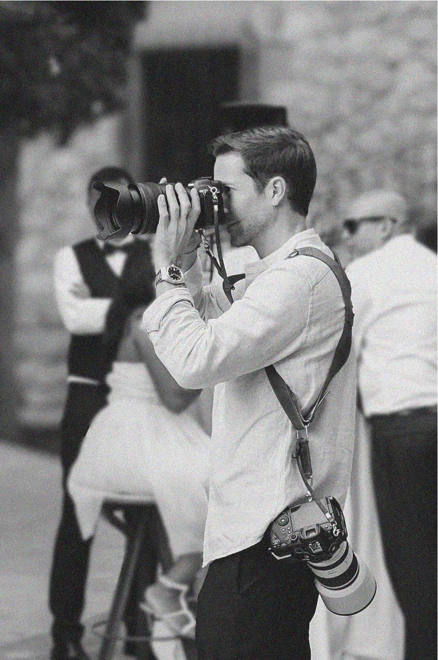 Man photographing with camera at outdoor wedding event.