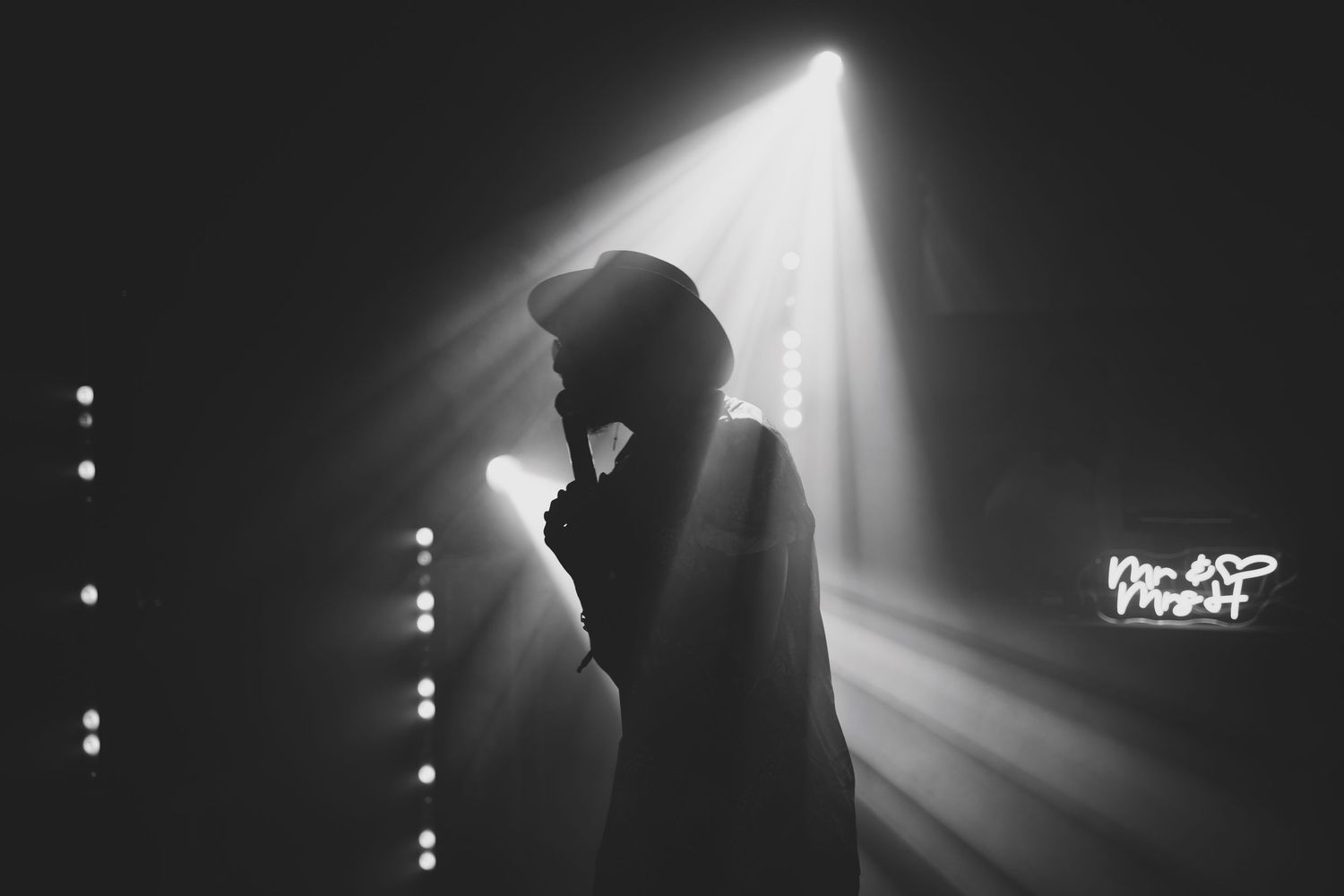 Dramatic black and white silhouette of singer performing under spotlight on stage.