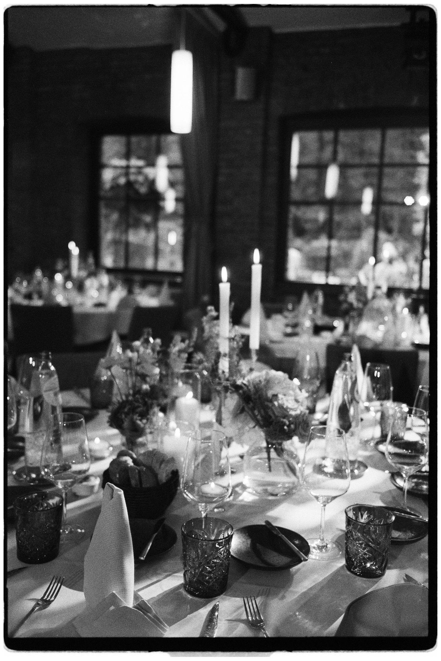 Elegant wedding reception table set with candles, crystal glasses, and floral centerpieces in black and white.
