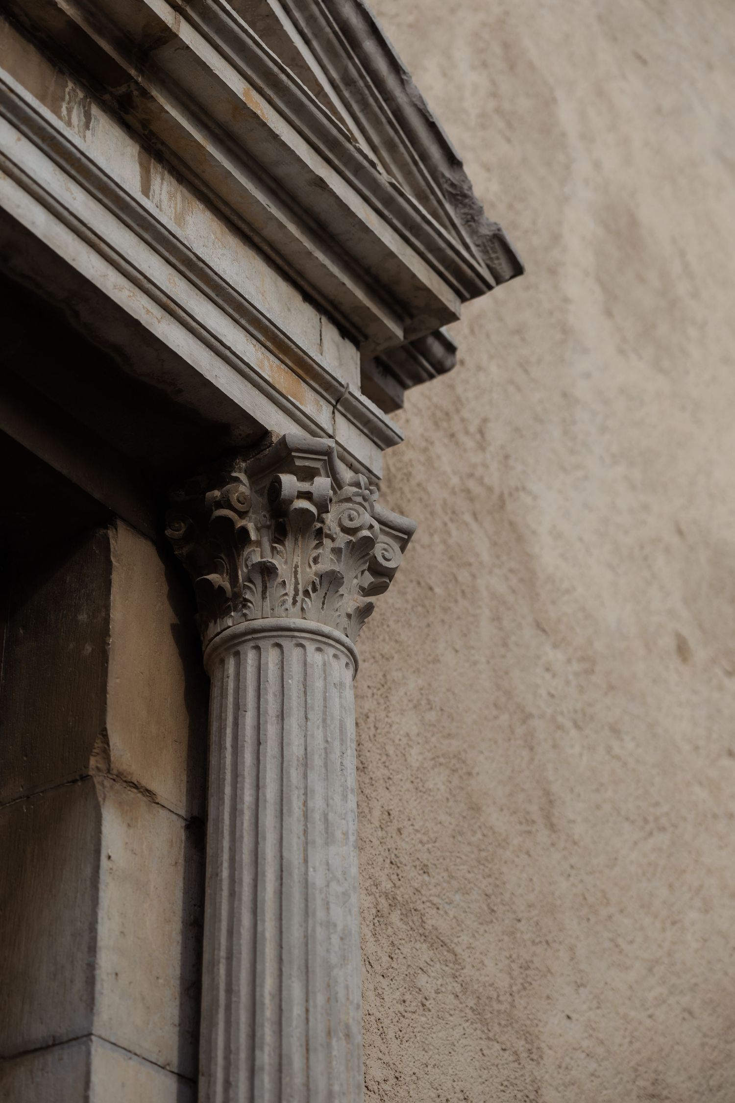 Ornate Corinthian column capital with detailed stone carving on classical architectural building exterior.
