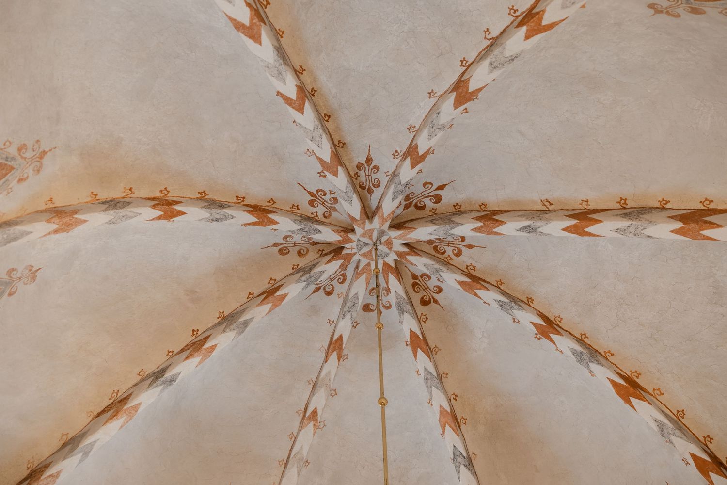 Ornate medieval church ceiling with star-shaped ribbed vaulting and decorative painted patterns.