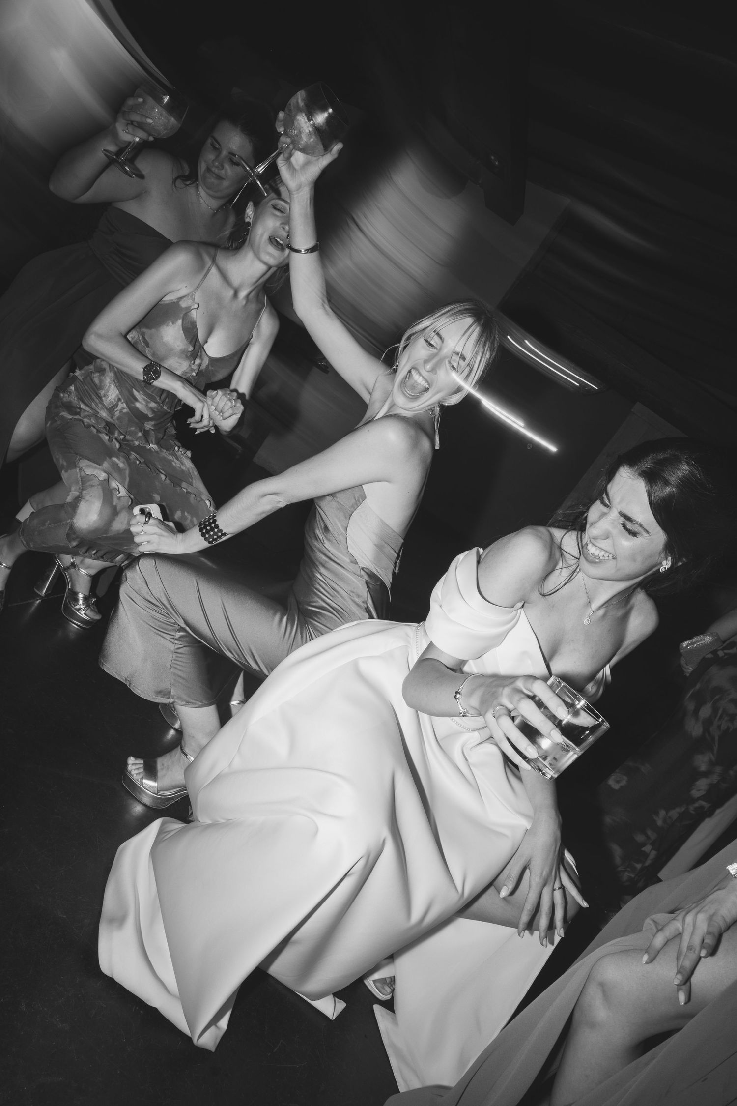 Black and white photo of bride and guests dancing energetically at wedding reception party.