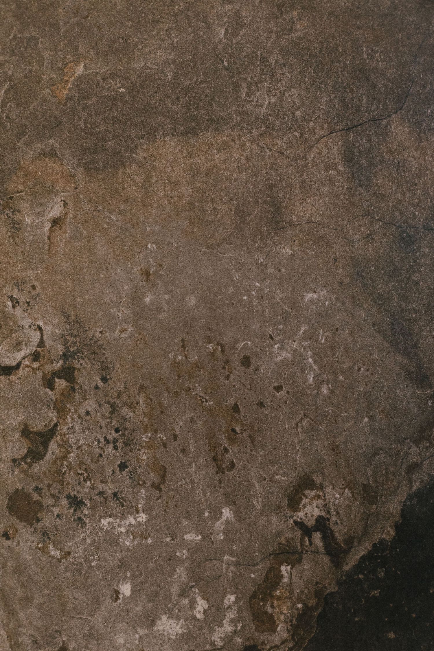 Close-up texture of aged brown stone surface with natural cracks and weathered patina.