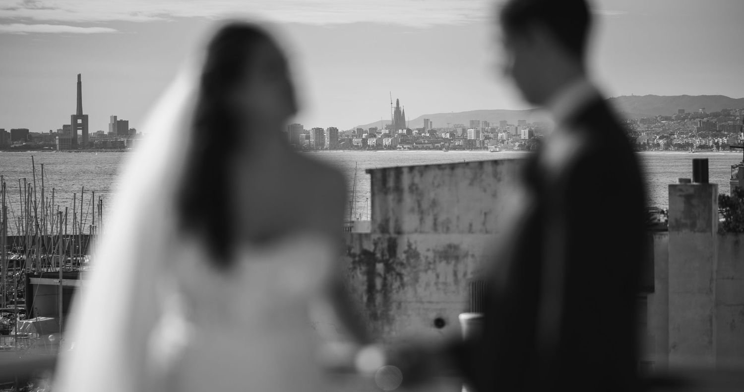 Black and white wedding photo of bride and groom with city skyline in background.