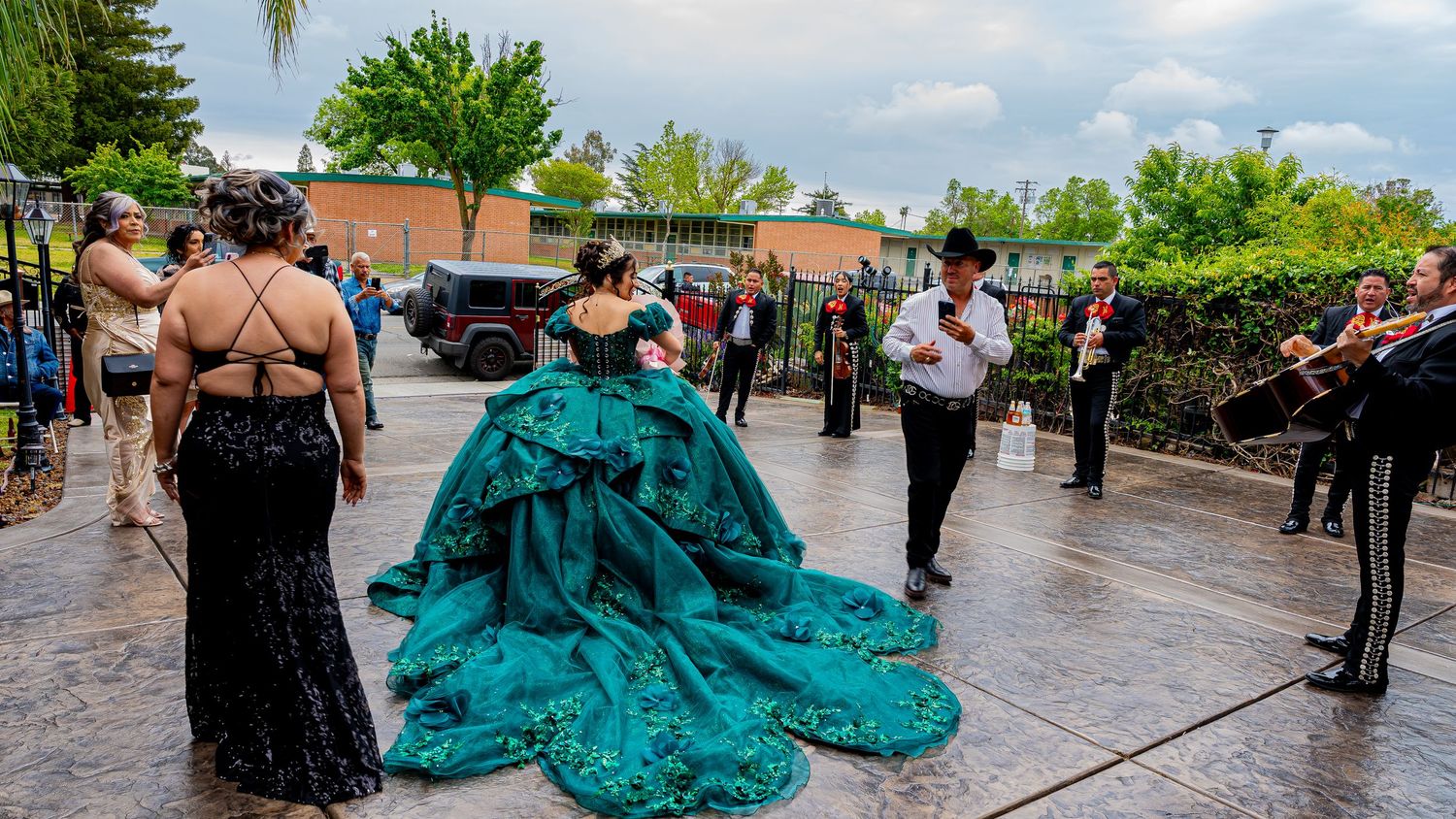 Wide shot of a festive outdoor gathering with guests and musicians in formal attire on a rainy day.