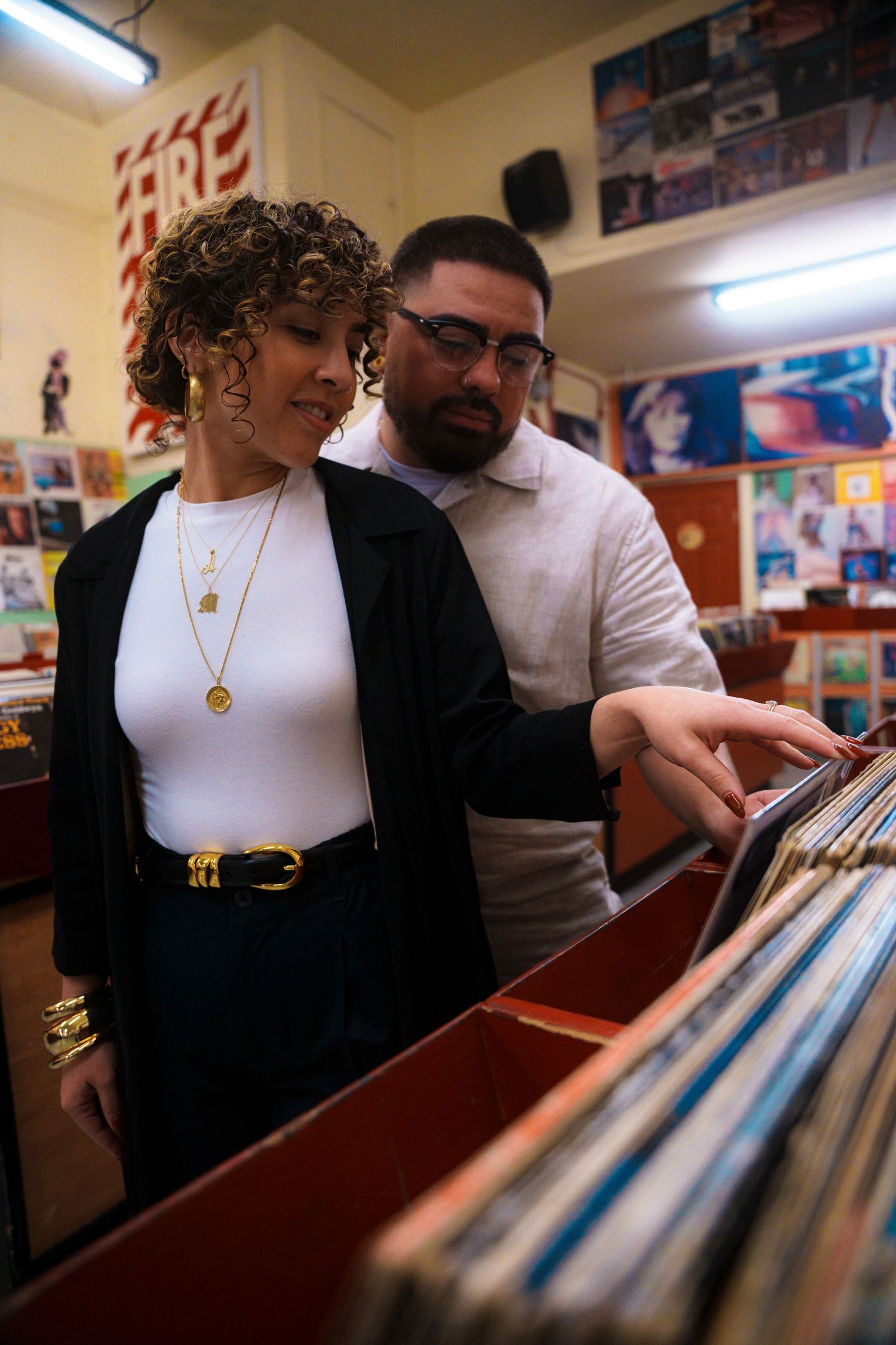 People browse through vinyl records at a record store while looking at albums in storage bins.