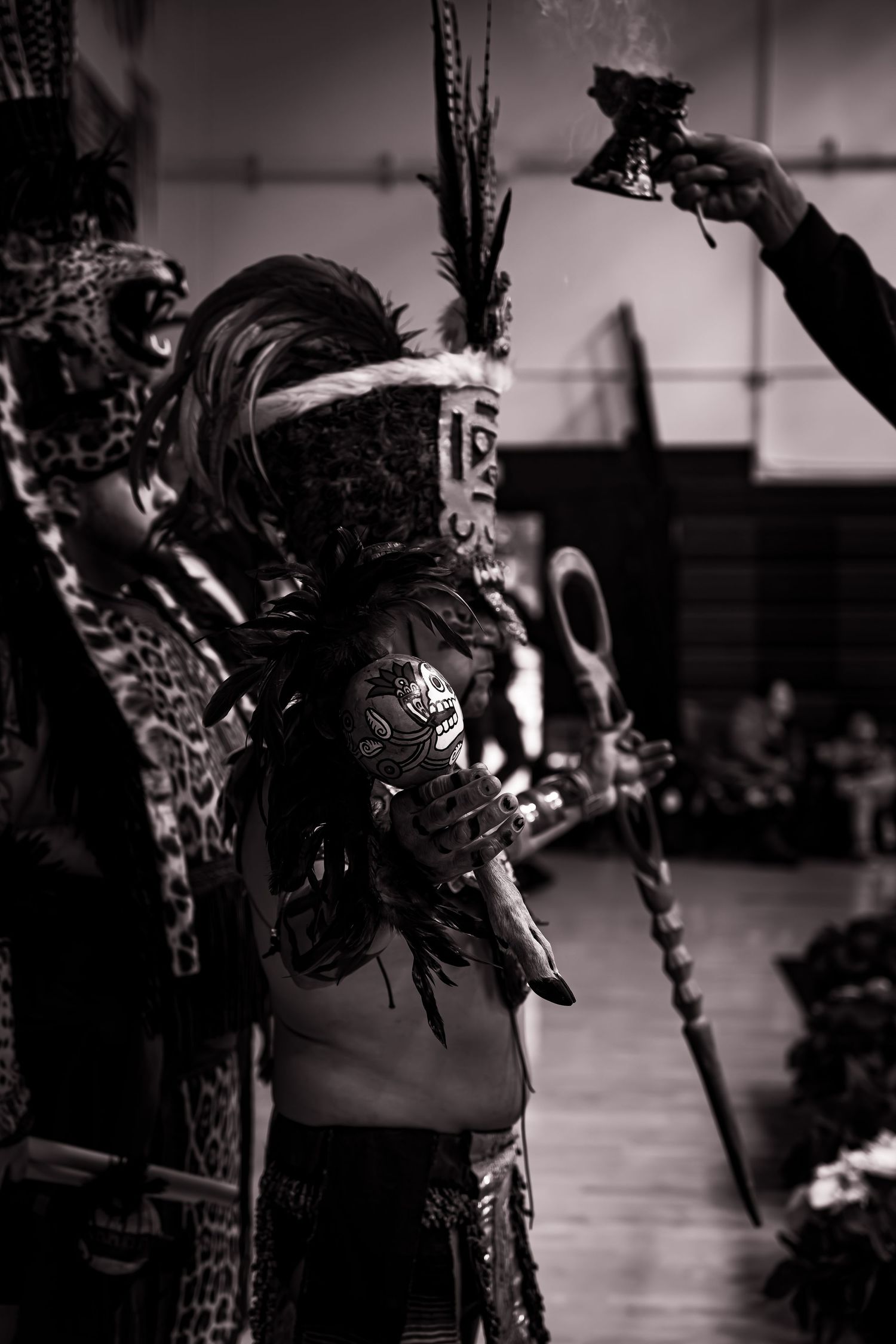 Black and white photo showing a series of dancers in traditional Mexican folkloric costumes performing on stage.