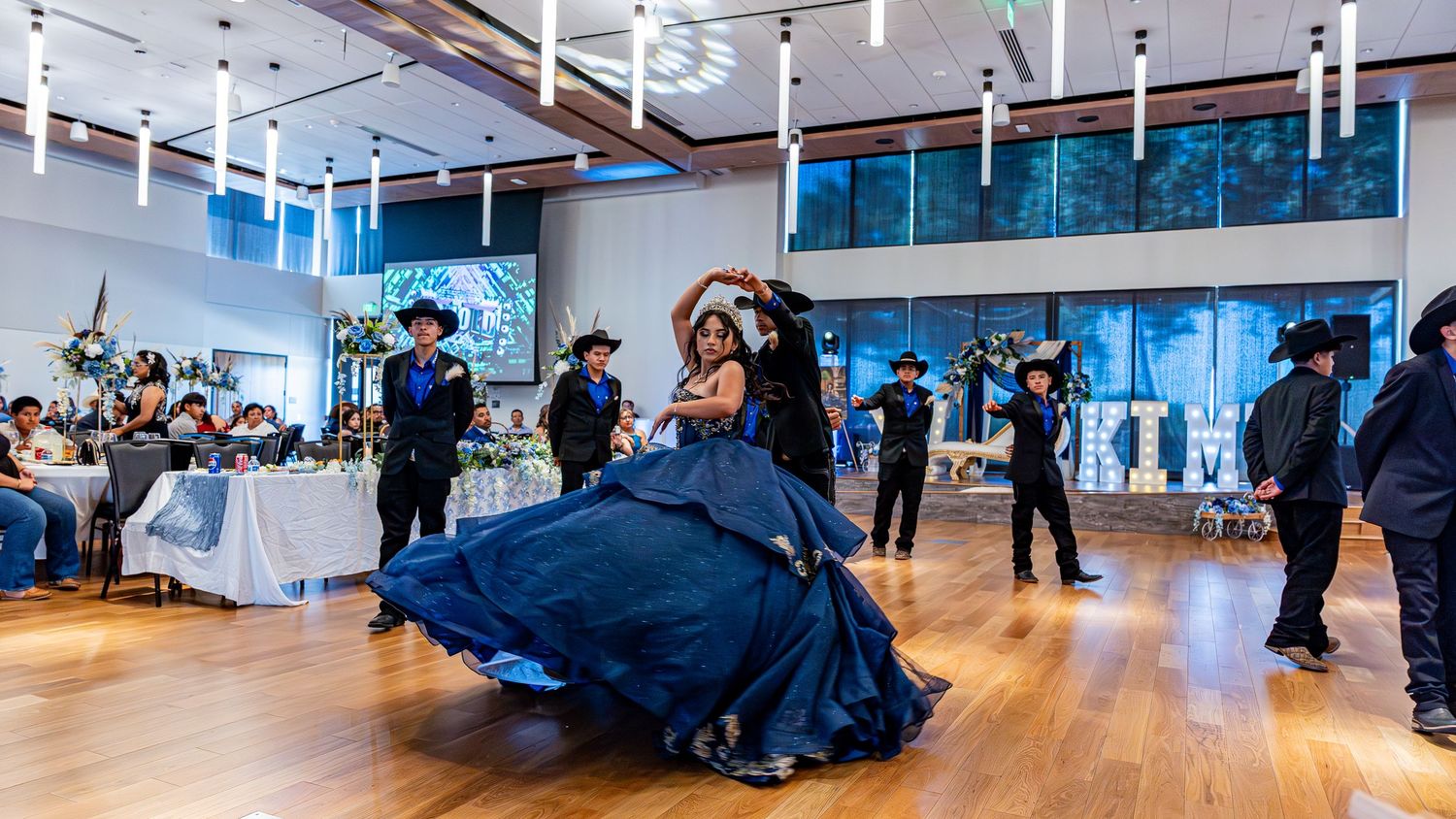 A wide-angle view of a modern event space with hardwood floors and hanging lights.