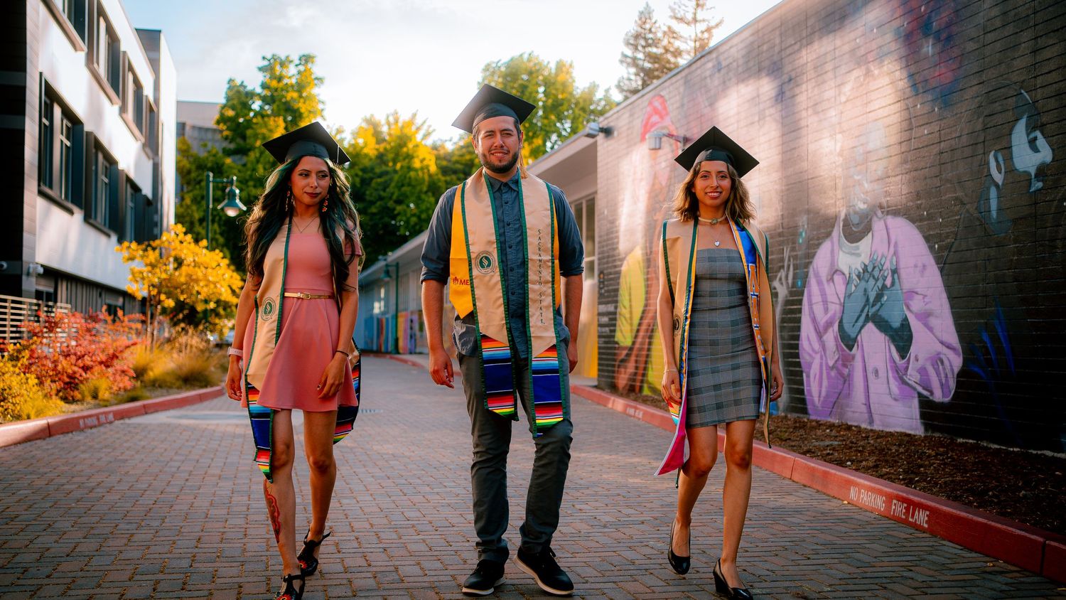 Panoramic view of graduates walking along a brick pathway during sunset.