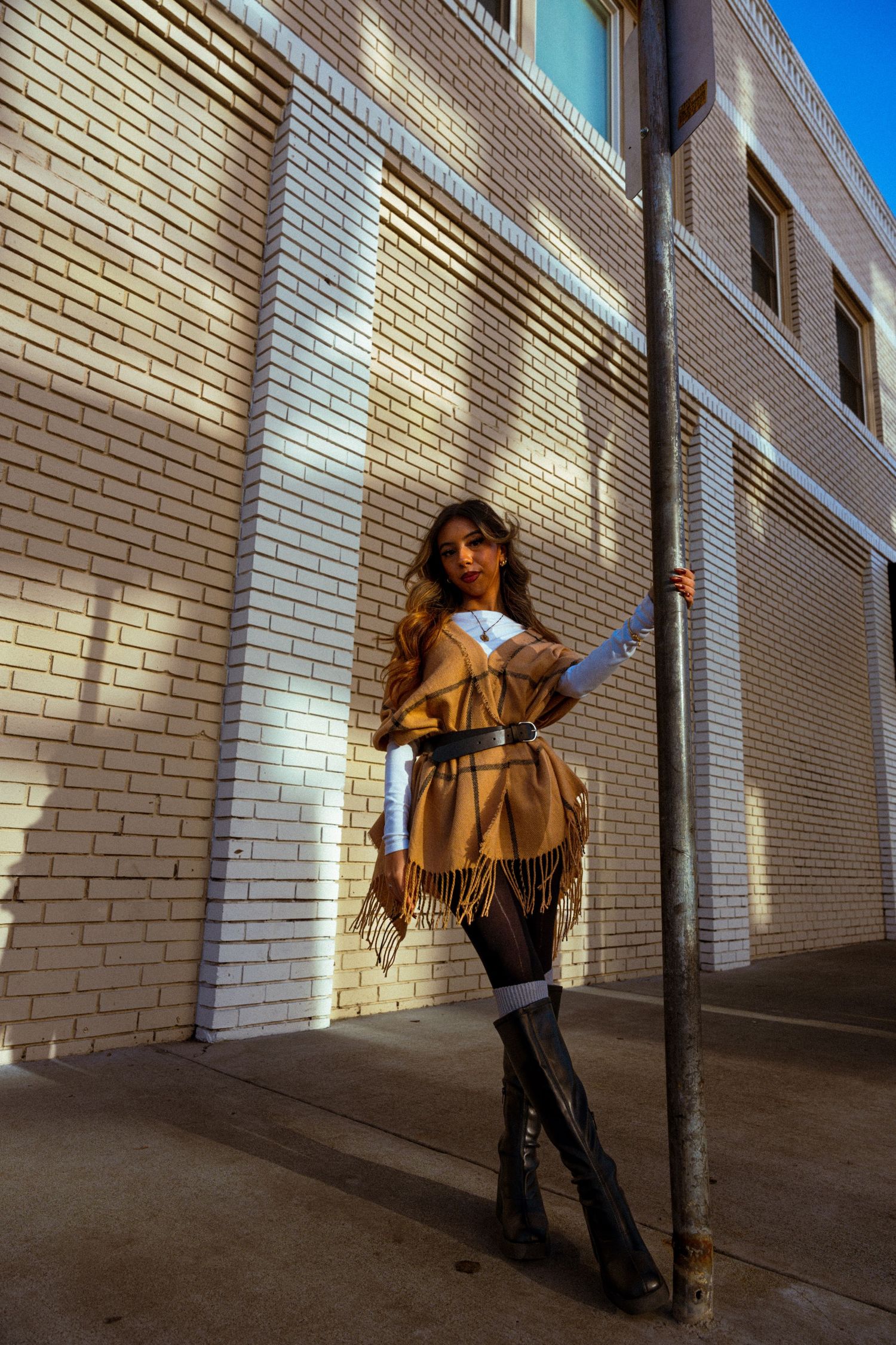 Urban fashion series featuring camel wrap and boots against architectural backdrop.
