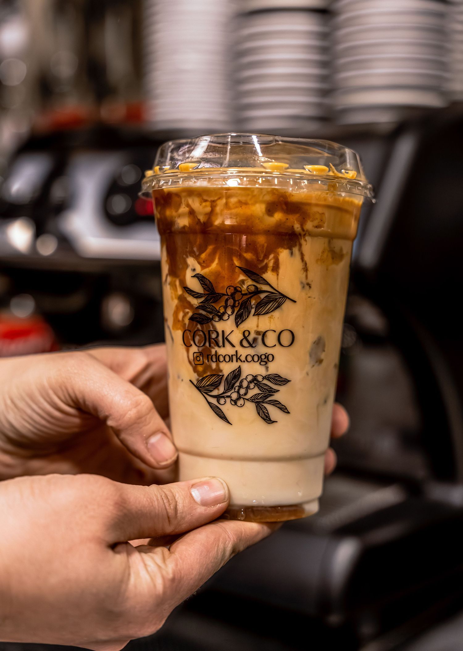 Two iced coffee drinks in branded plastic cups being served.
