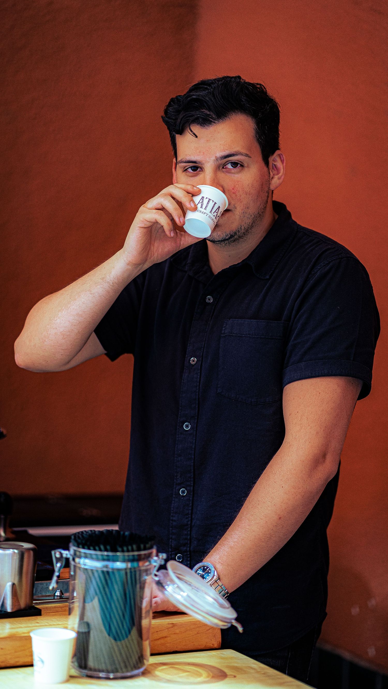 Barista in black shirt smelling coffee for quality assessment.