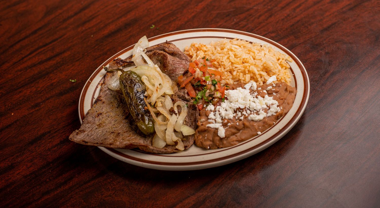 Close-up of Mexican-style dishes with melted cheese on brown plates.