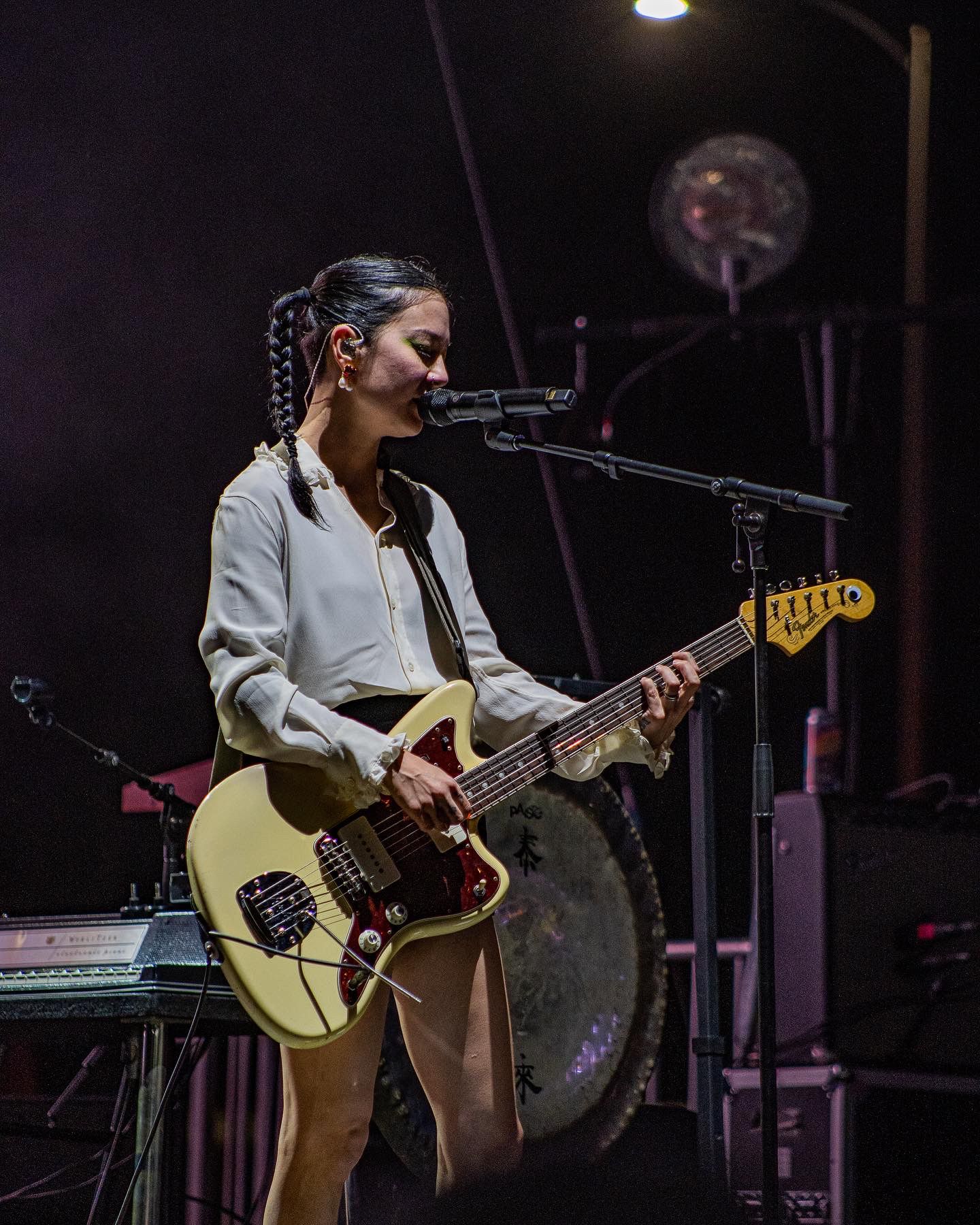 Musician performing with electric guitar on dimly lit stage.