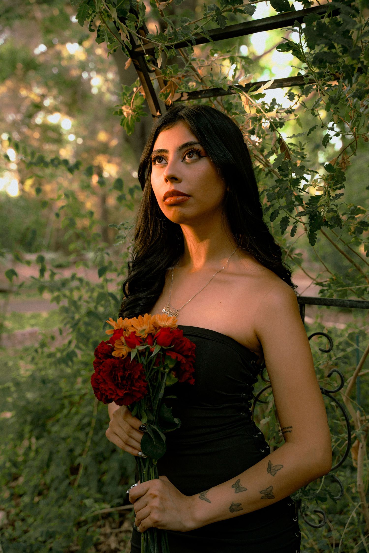 A series of moody outdoor portraits with dark red roses against lush green foliage in natural lighting.
