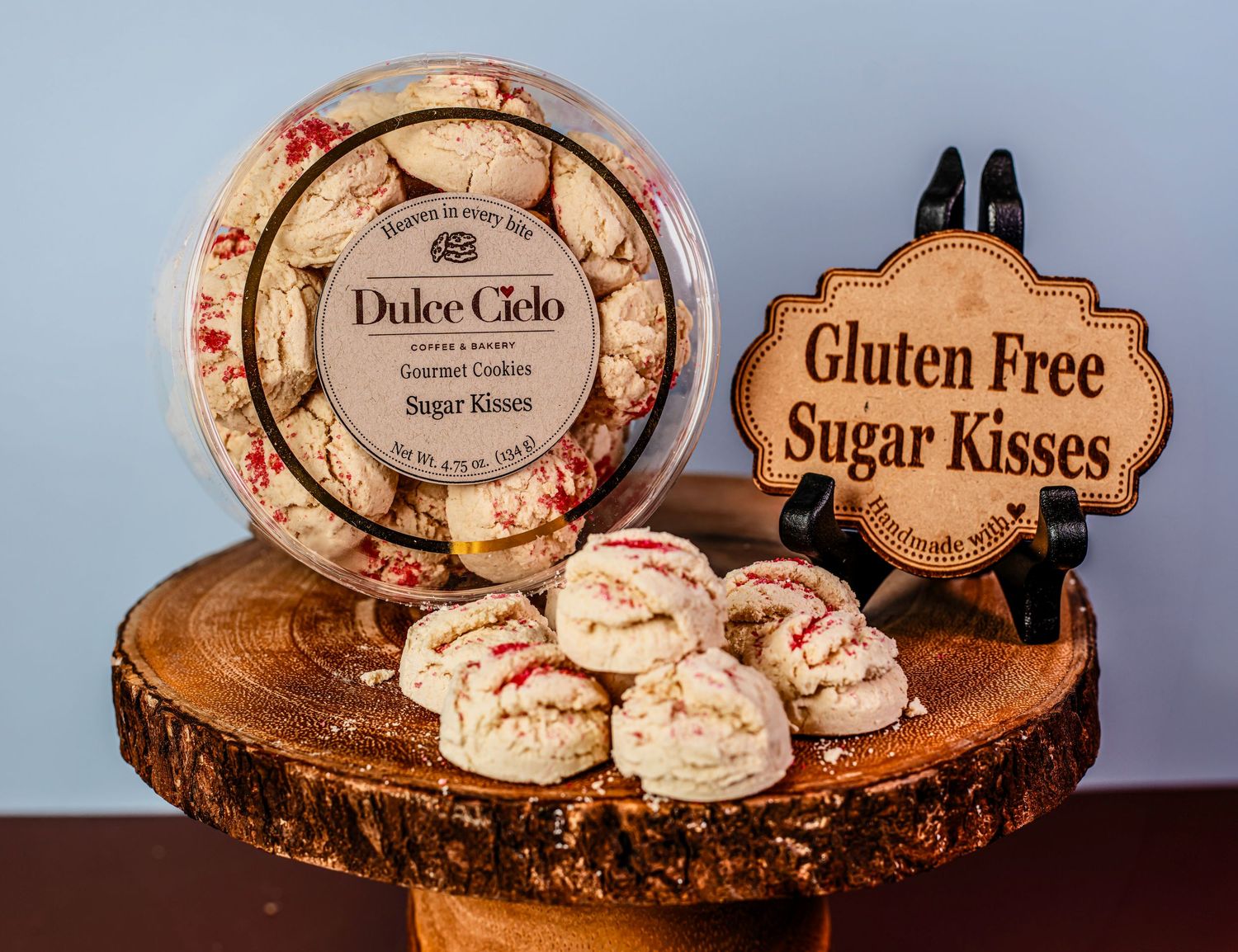 Gluten-free sugar kisses cookies displayed on rustic wooden slices with decorative labels and packaging.