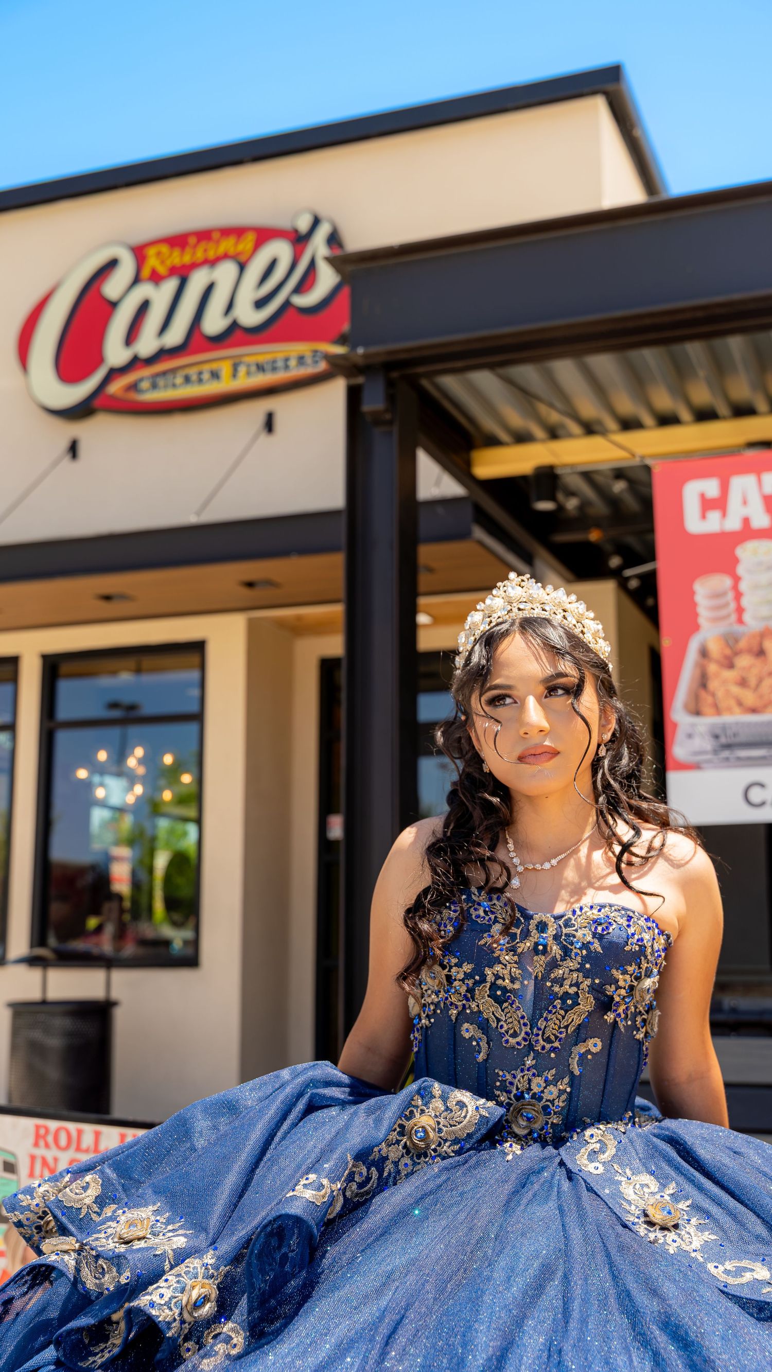 A stunning navy blue quinceañera gown with intricate beading photographed in front of a storefront.