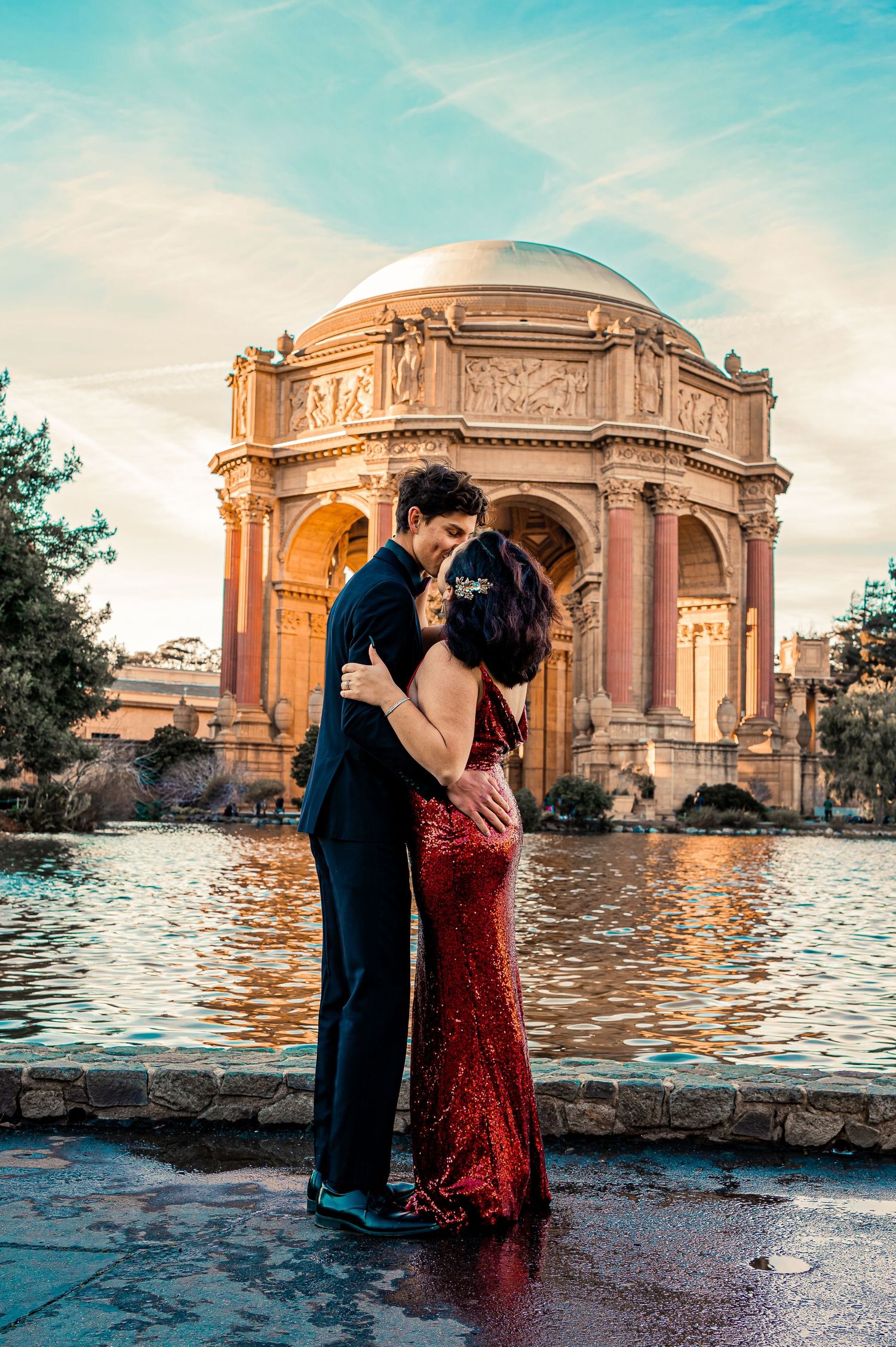 Romantic couple in formal wear poses by the Palace of Fine Arts in San Francisco at sunset.