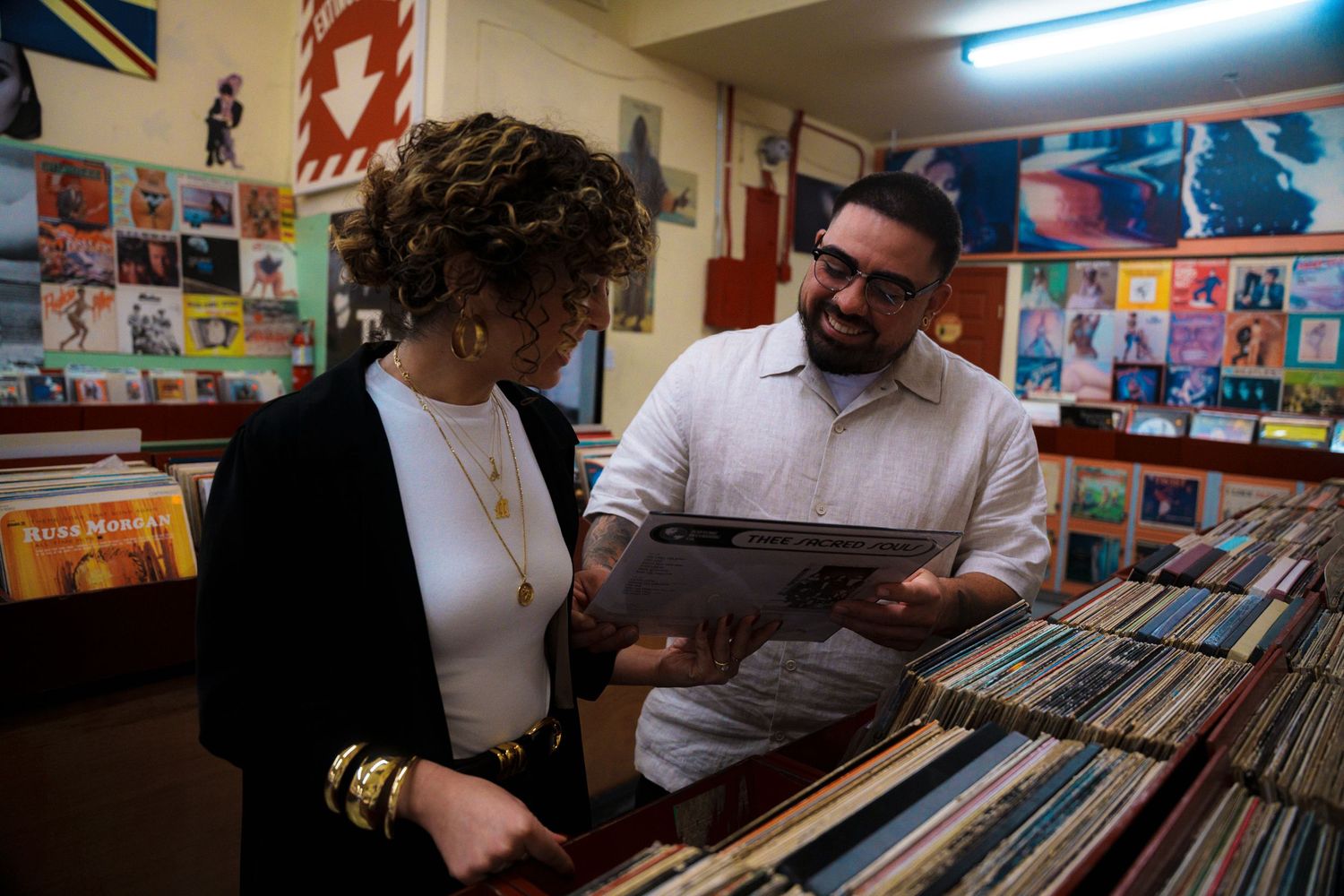 Browsing through vinyl records at a music store with album covers on display.