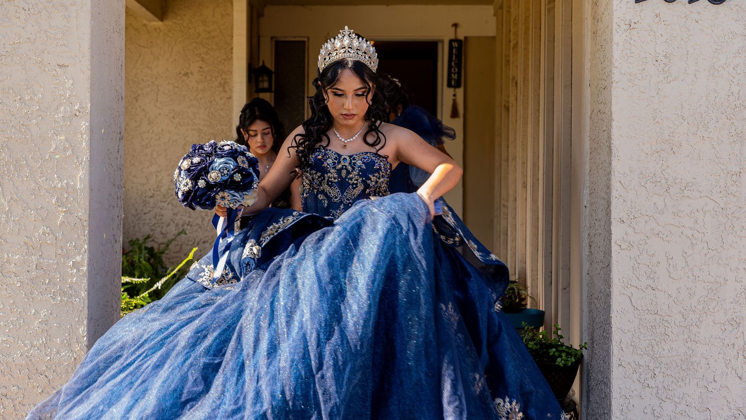 An elegant blue ball gown creates a dramatic silhouette against classic architectural columns.