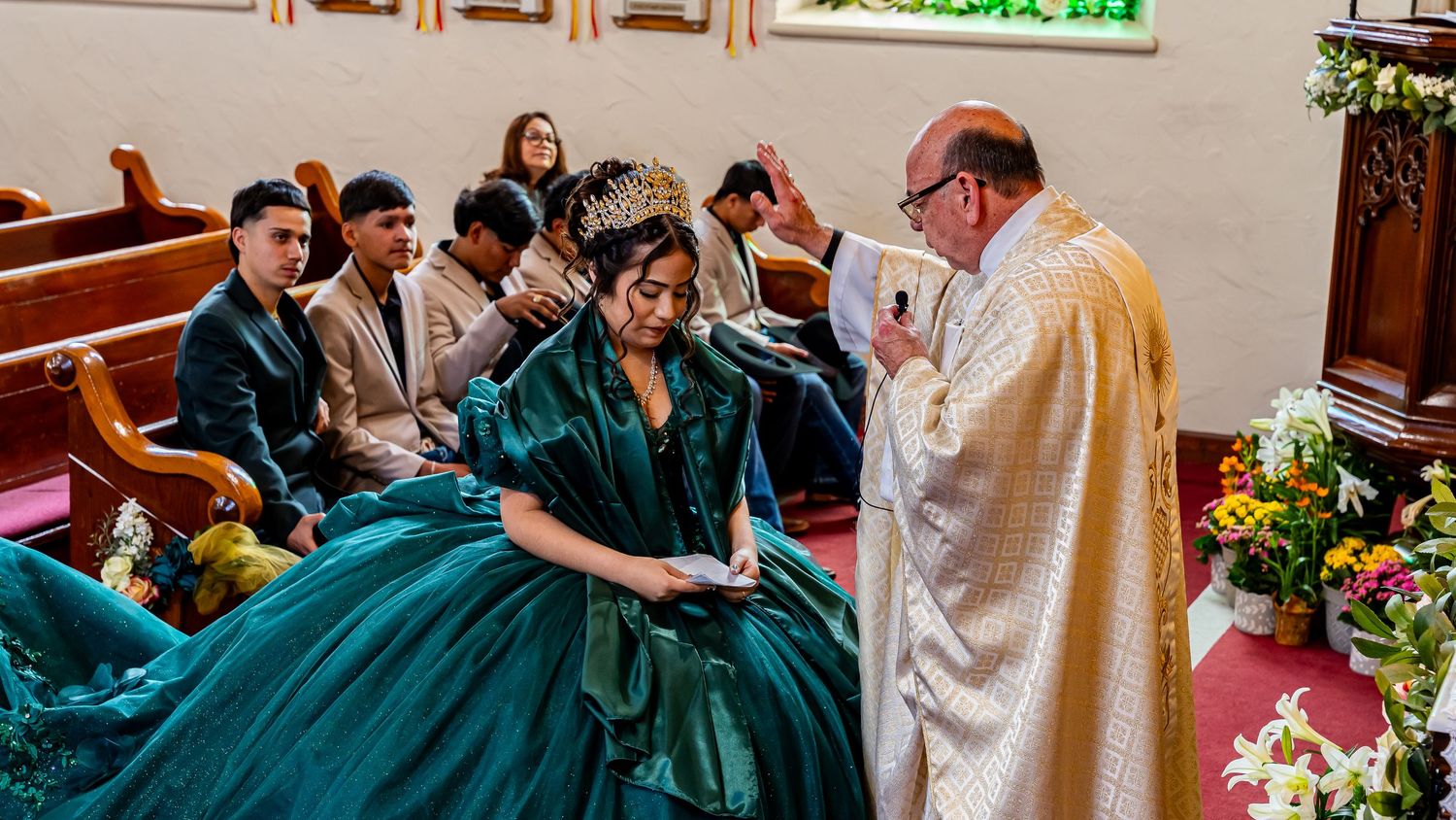Panoramic view of a religious ceremony inside a church with red carpeting and wooden pews.