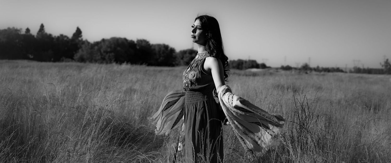 Black and white panoramic photo series showing a person walking through a grassy meadow on a sunny day.