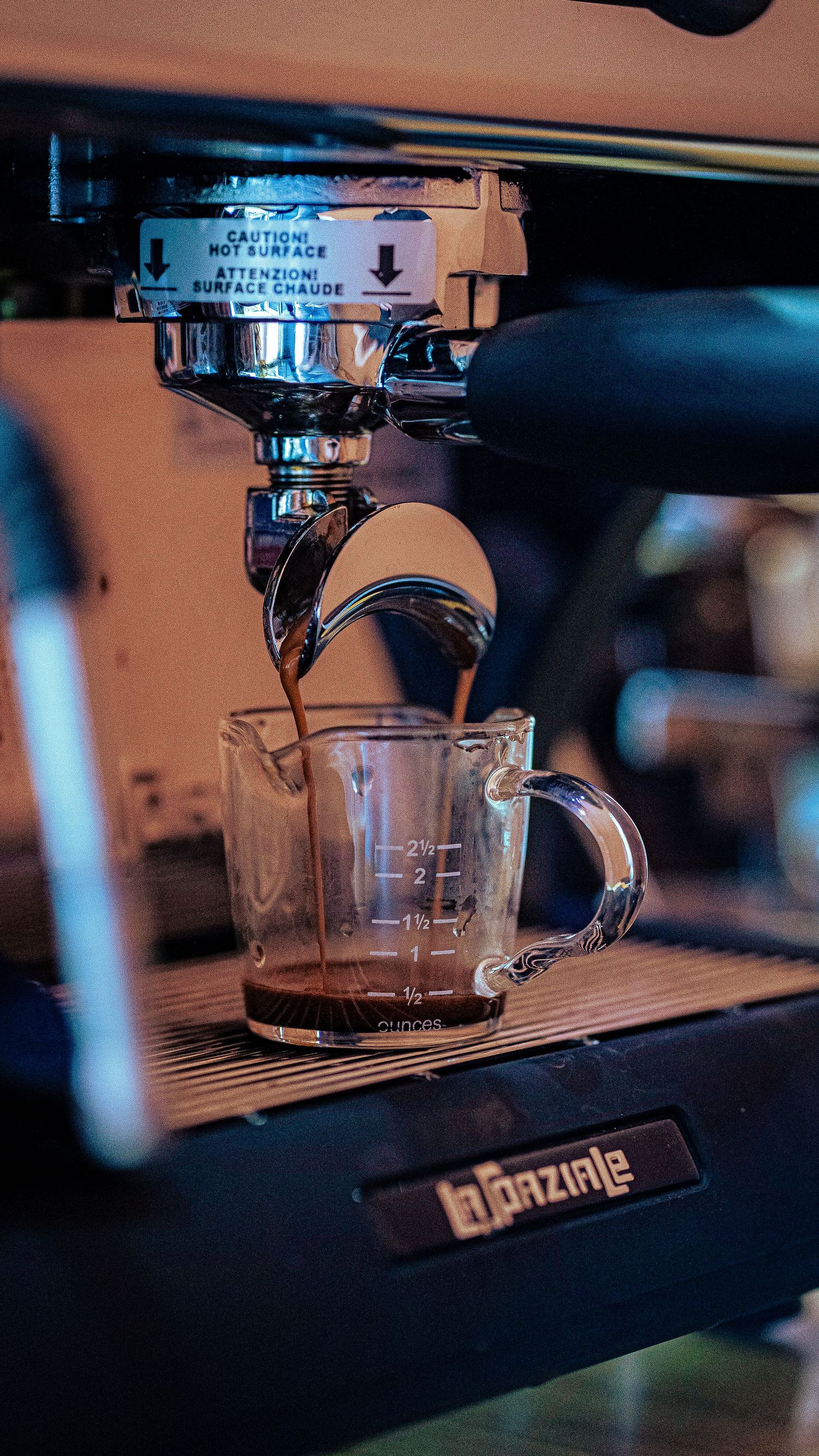 Close-up of an espresso machine brewing coffee into glass cups.