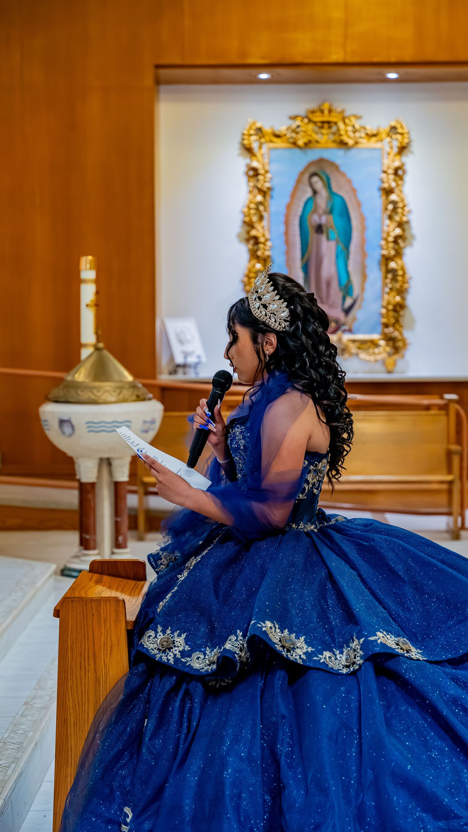 A sparkling navy blue quinceañera dress fills the frame in an ornate church setting.