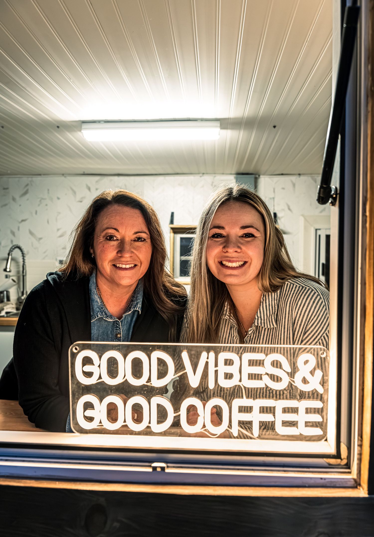 Neon sign reading 'GOOD VIBES & GOOD COFFEE' illuminated against white wall.