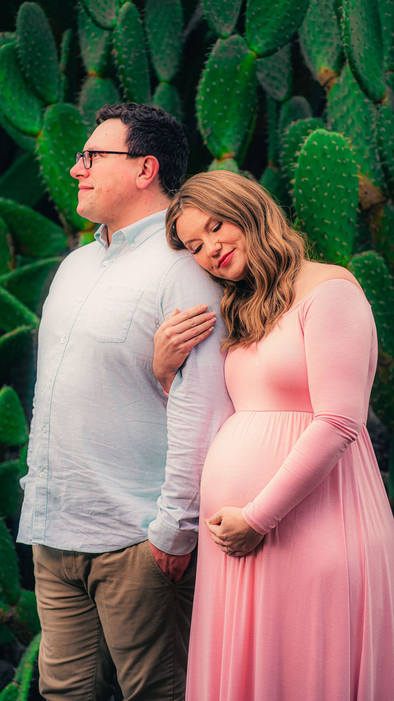 Romantic couple moment captured against lush green cactus background.