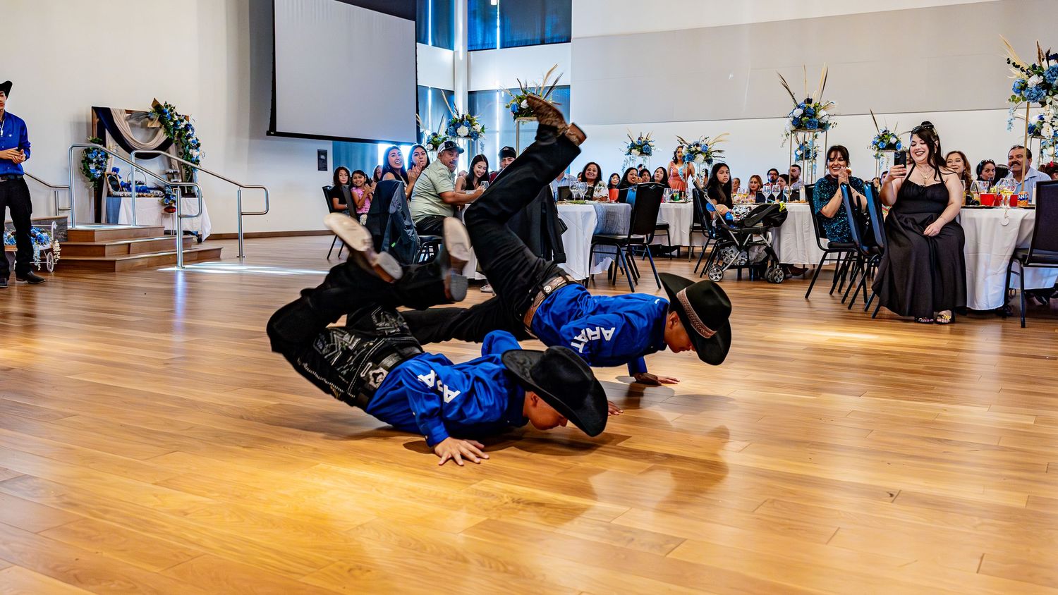 Panoramic view of a large dance studio with wooden floors and mirrored walls filled with people dancing.