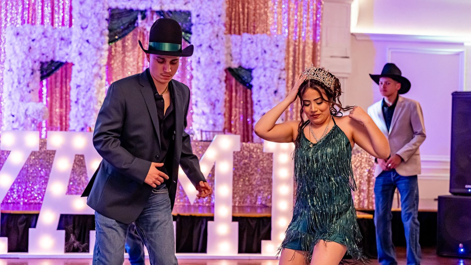 Event space decorated with string lights and filled with dancers in formal attire.