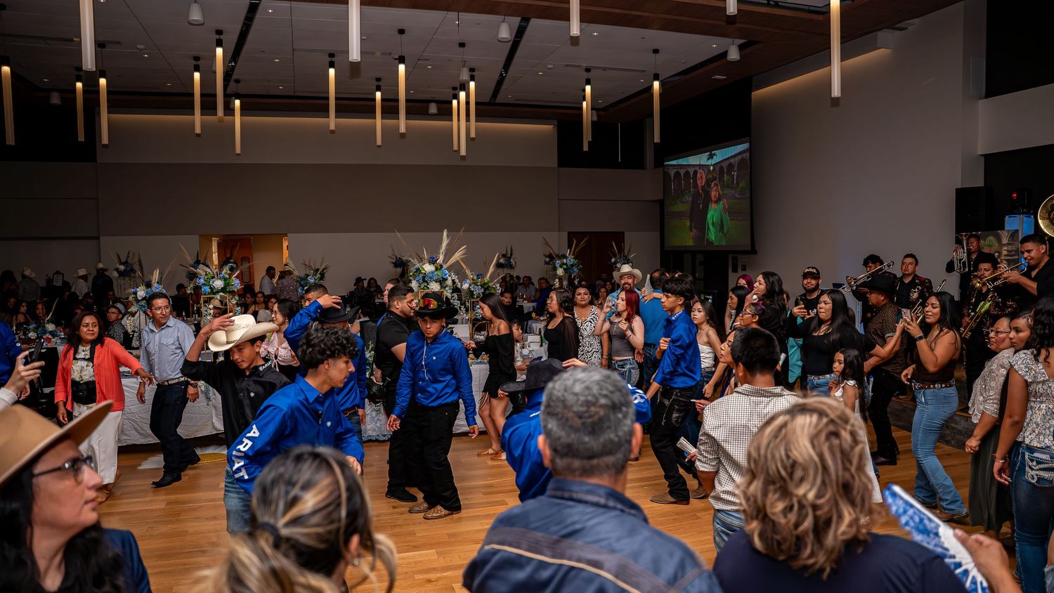 Wide angle view of a dance hall filled with people during a social gathering.