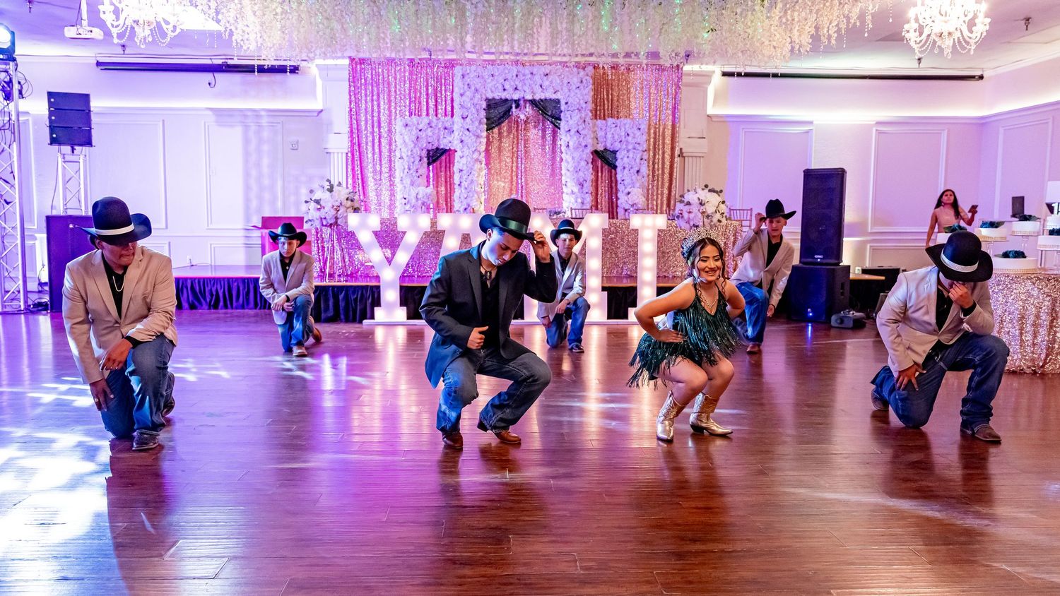 Panoramic view of a ballroom event with purple lighting and dancing guests.
