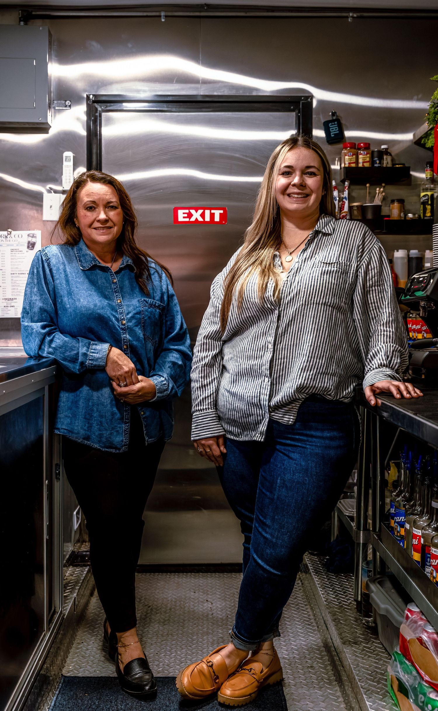 People in casual attire standing in storage room with EXIT sign visible.