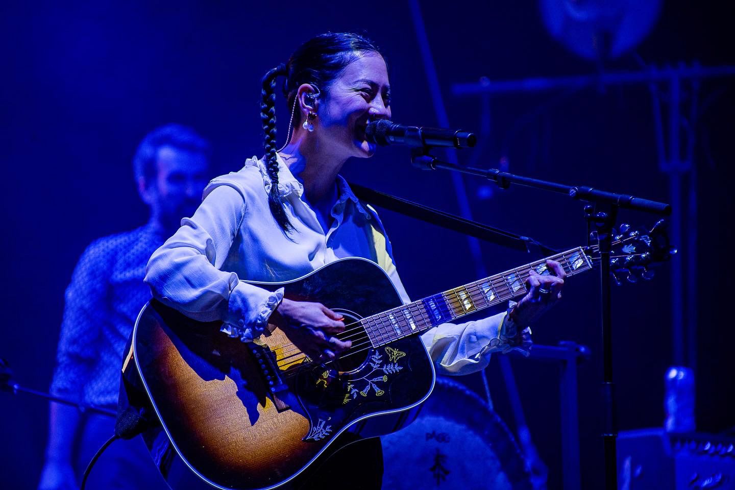 Live music performance with blue stage lighting and acoustic guitar.