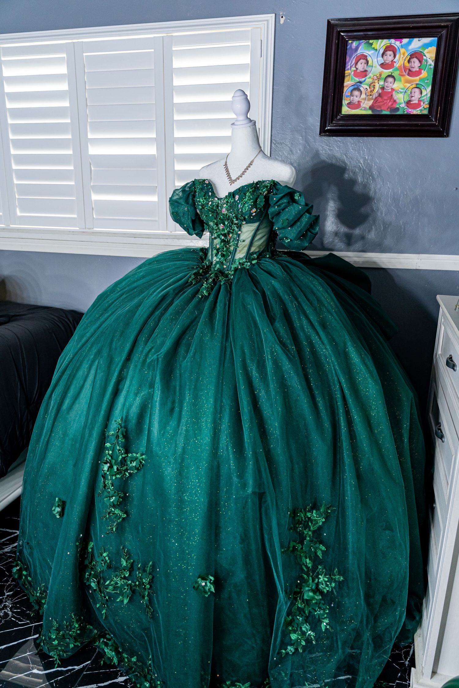 Elegant emerald green ball gown with embellished details displayed on mannequin.