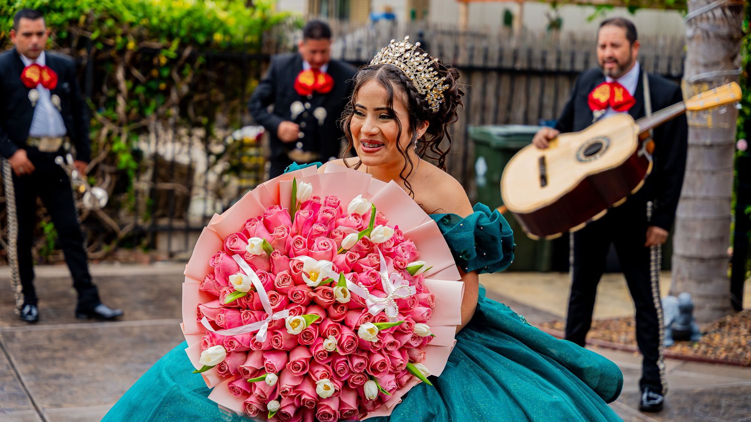Celebratory scene featuring a teal gown and pink flower bouquet during an outdoor event.