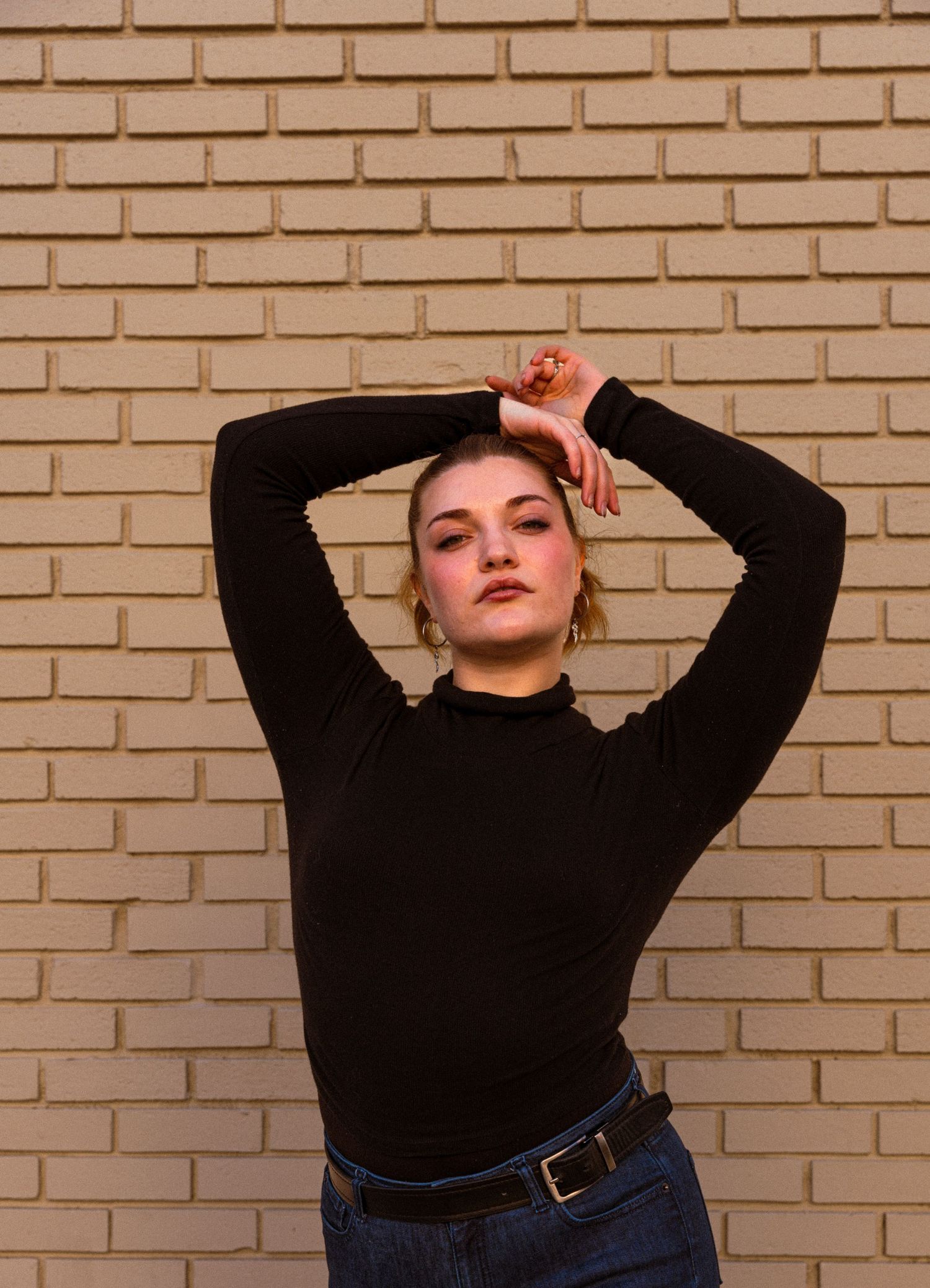 Fashion portraits against brick wall showing casual black top and jeans outfit.