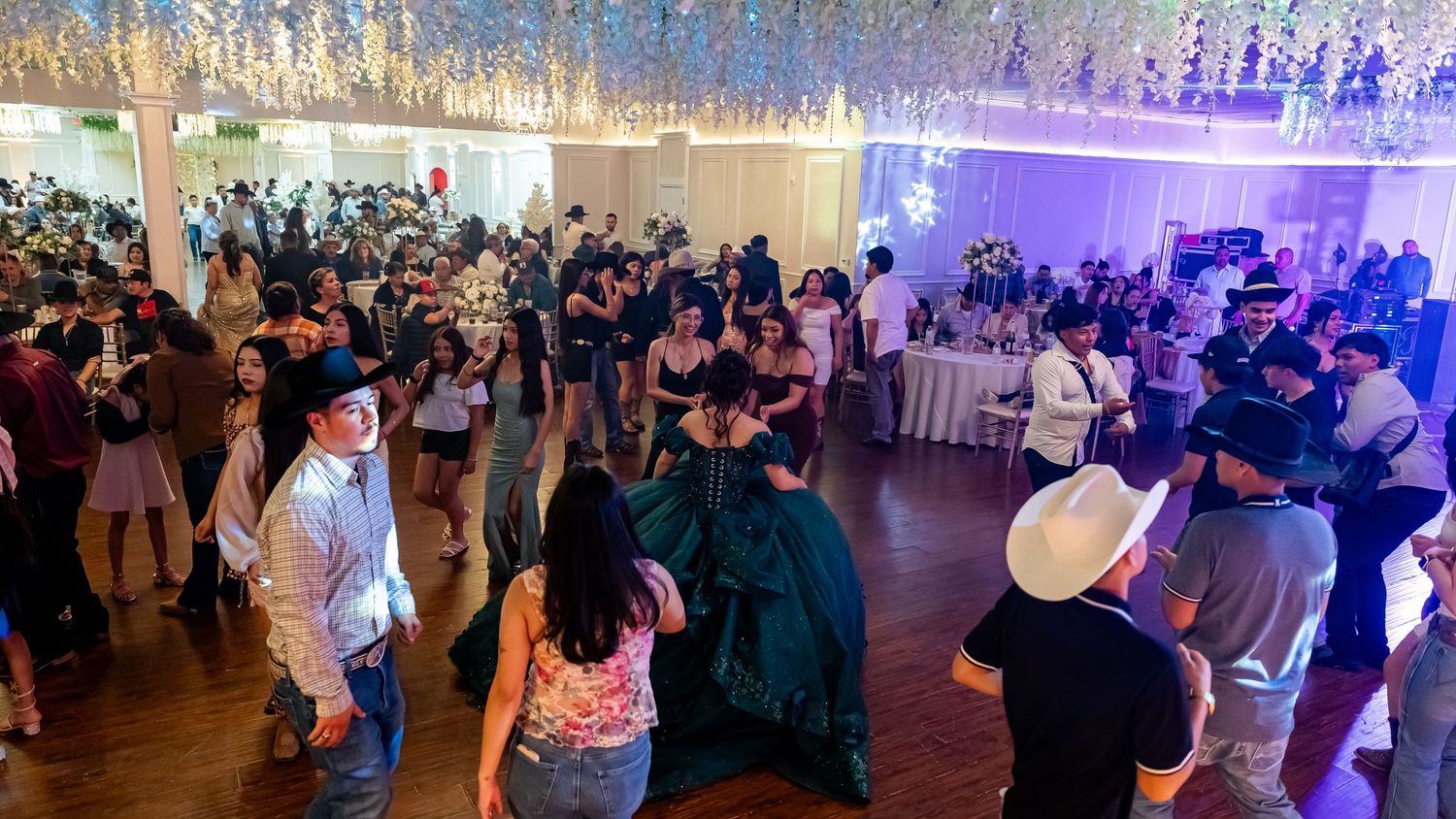 Panoramic view of a crowded ballroom event with dramatic blue and purple lighting.