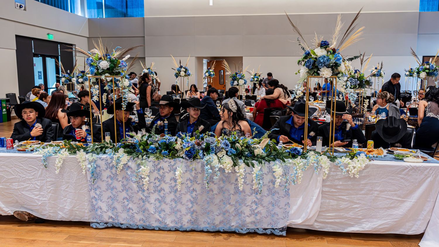 A decorated banquet hall with teal and white floral centerpieces and table settings.
