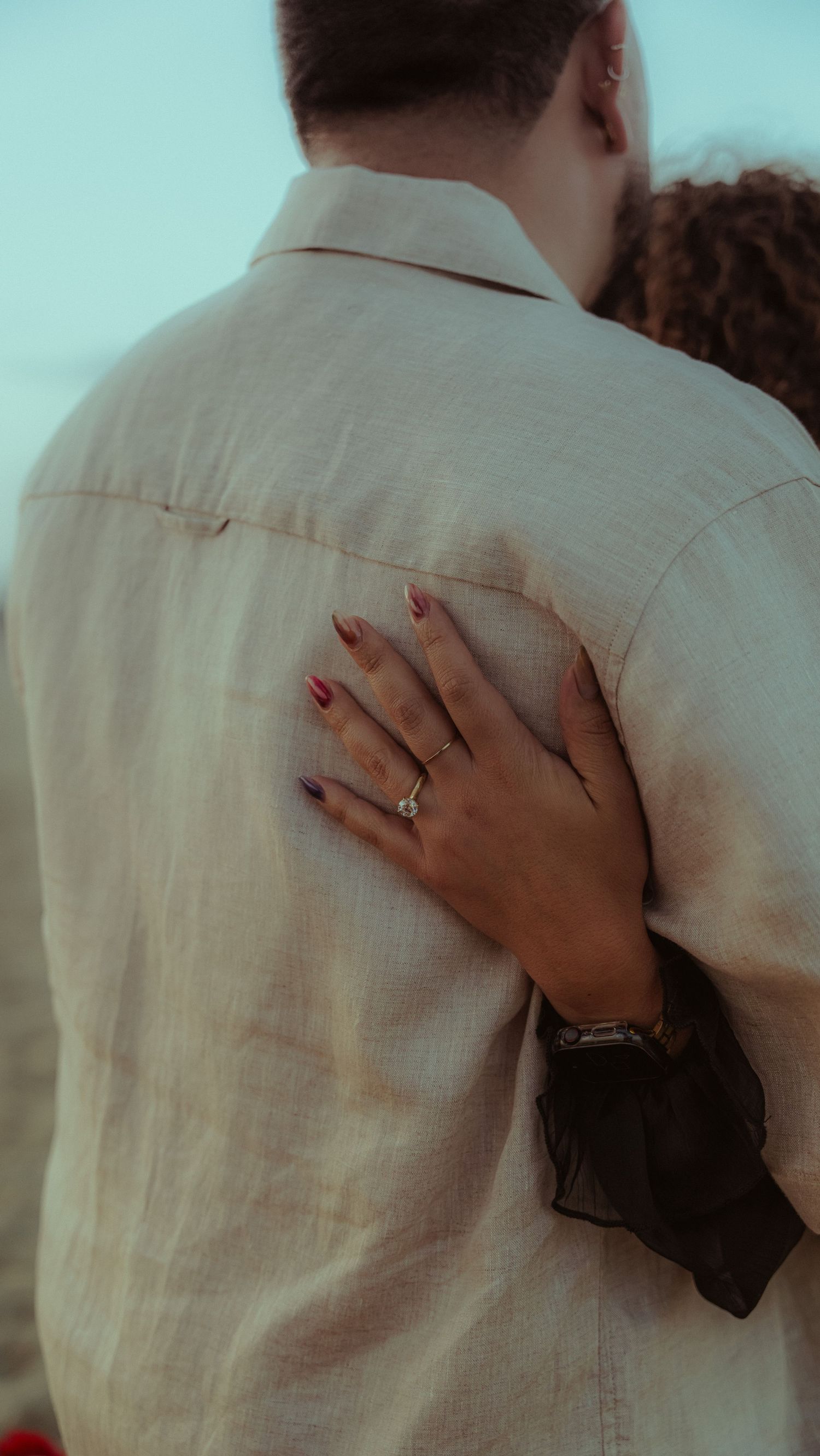 Close-up shots of a couple embracing, showing a ring on their hand.