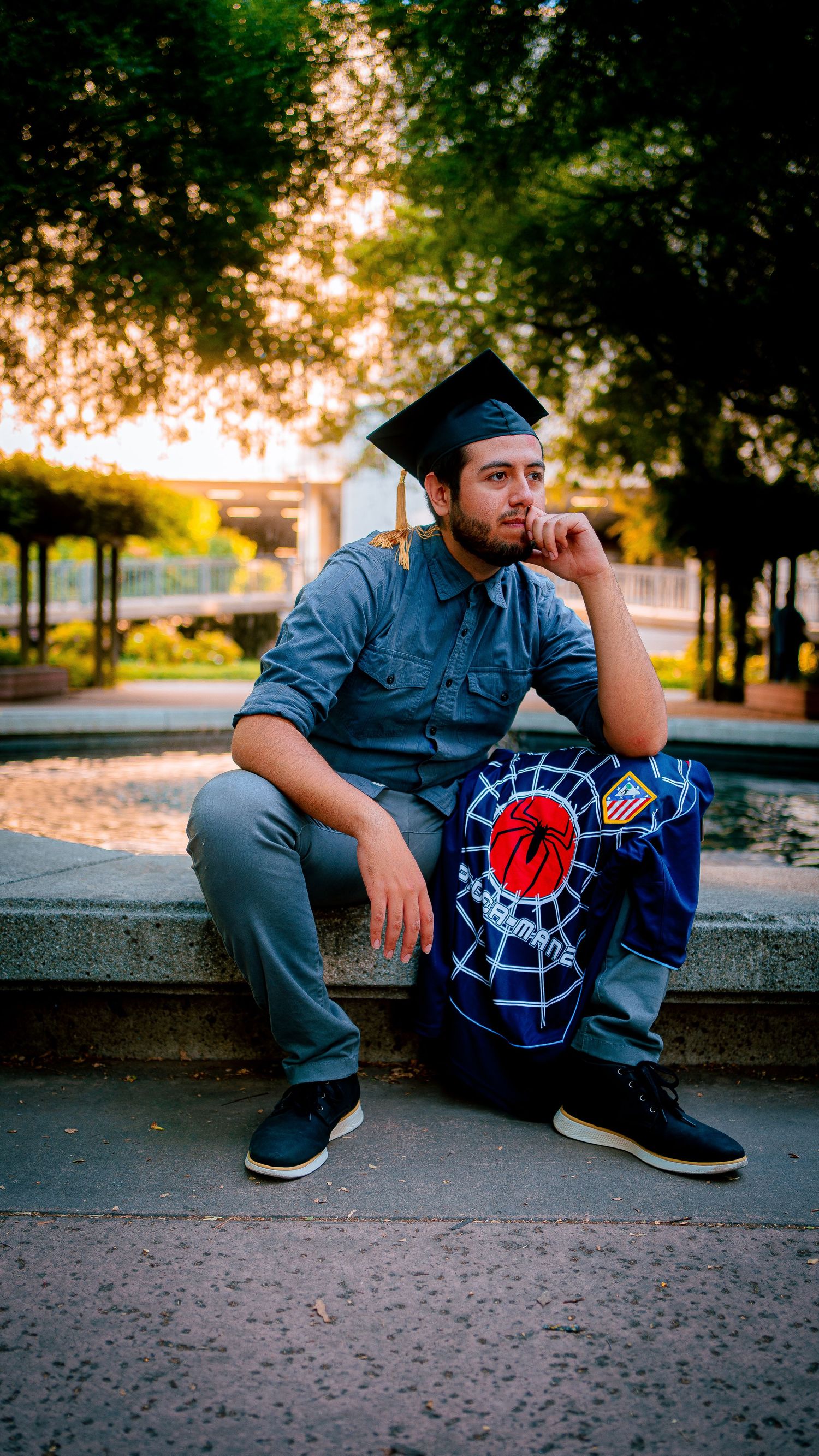 Person in denim sitting on concrete steps at sunset wearing a graphic t-shirt.
