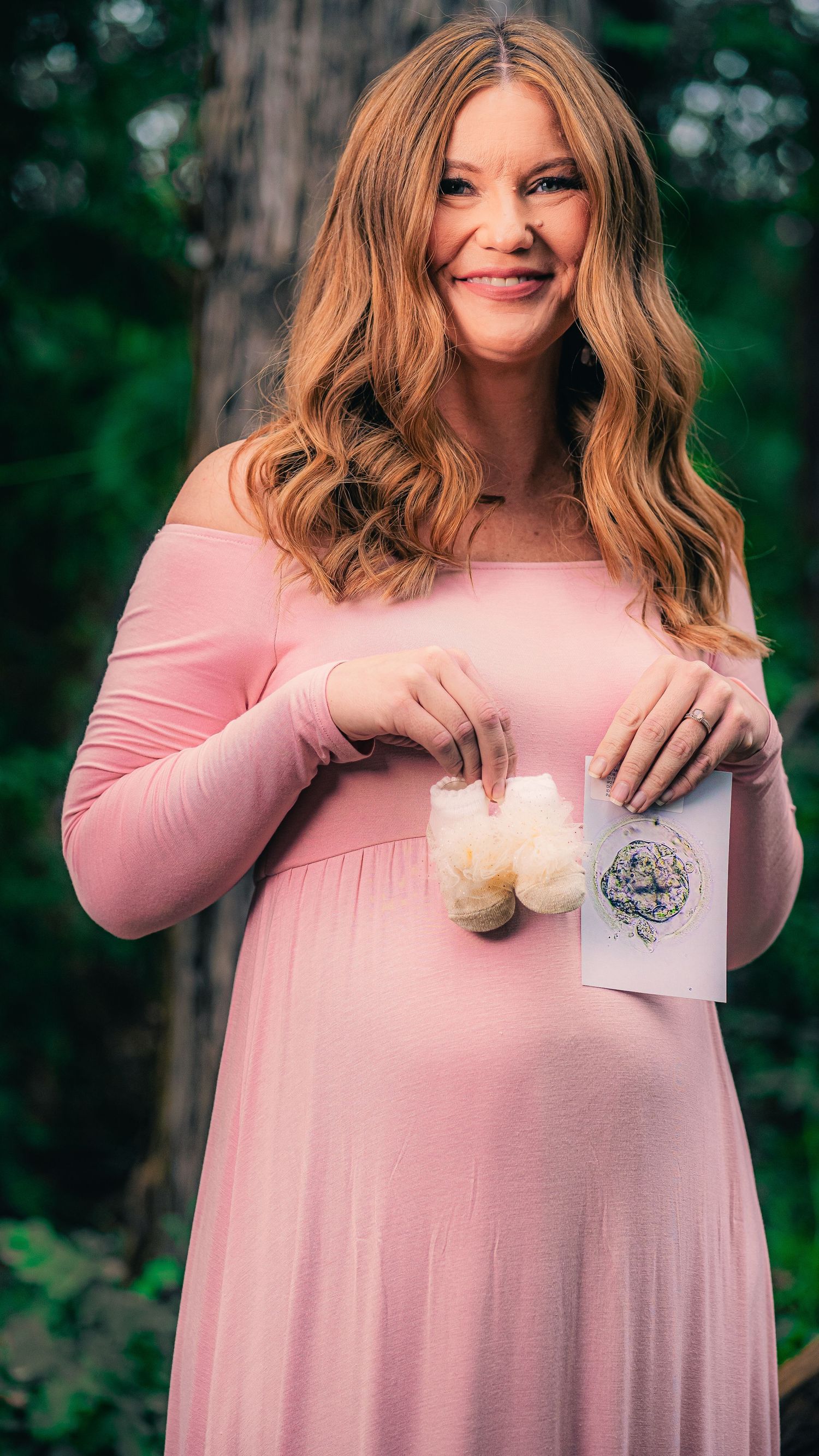 Pink maternity dress photo series with forest backdrop and natural lighting.