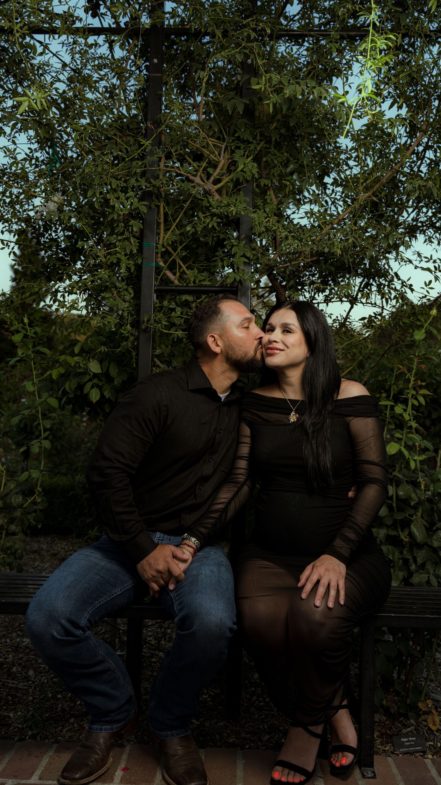 An intimate moment shared between a couple on a garden bench.