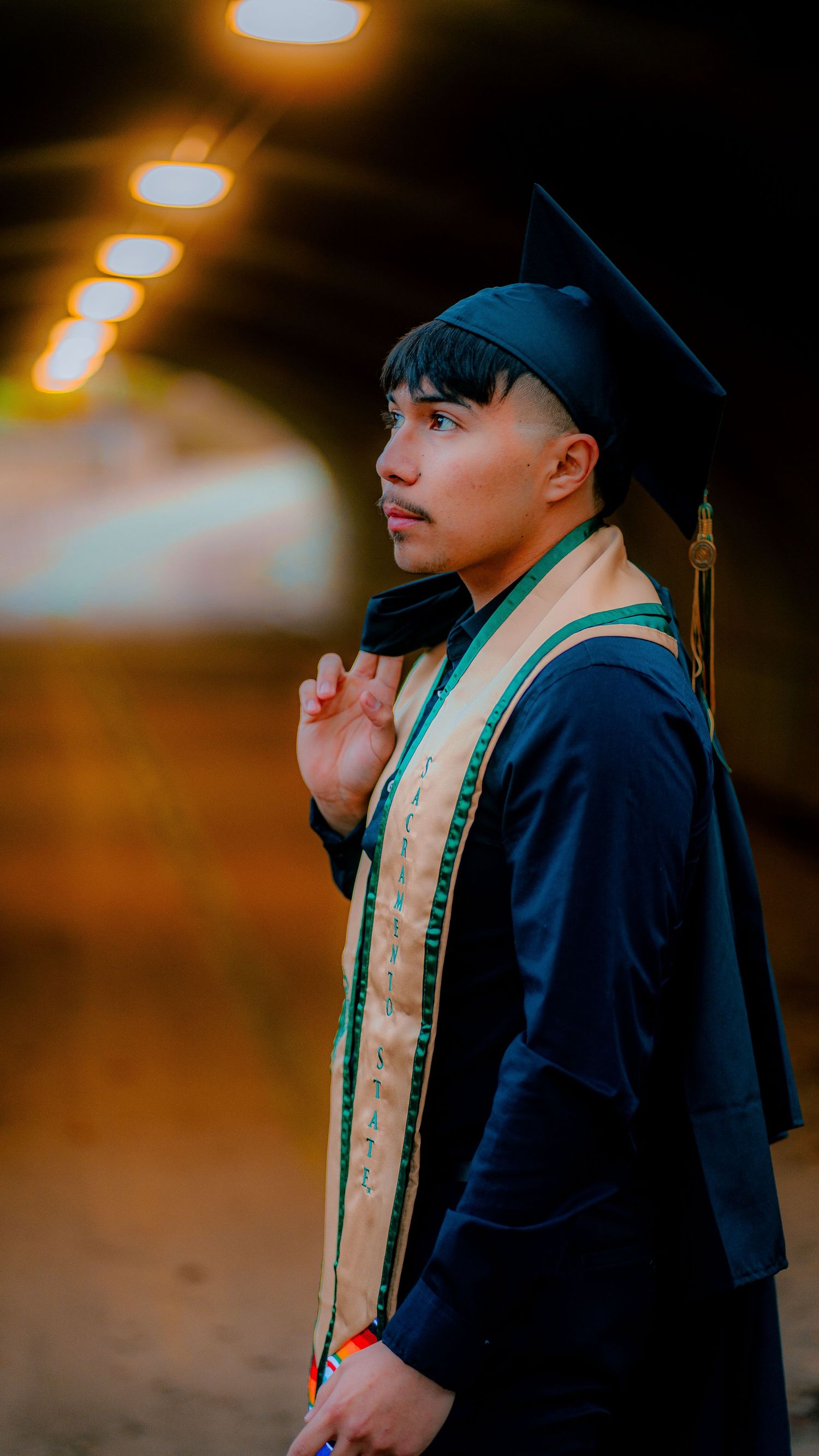 Graduation portrait series in moody lighting with graduate in cap and stole.