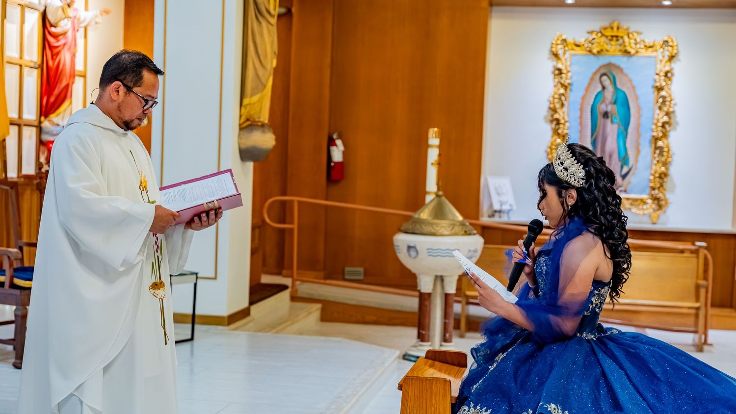 A royal blue ball gown creates an elegant scene in a church with golden-framed religious artwork.